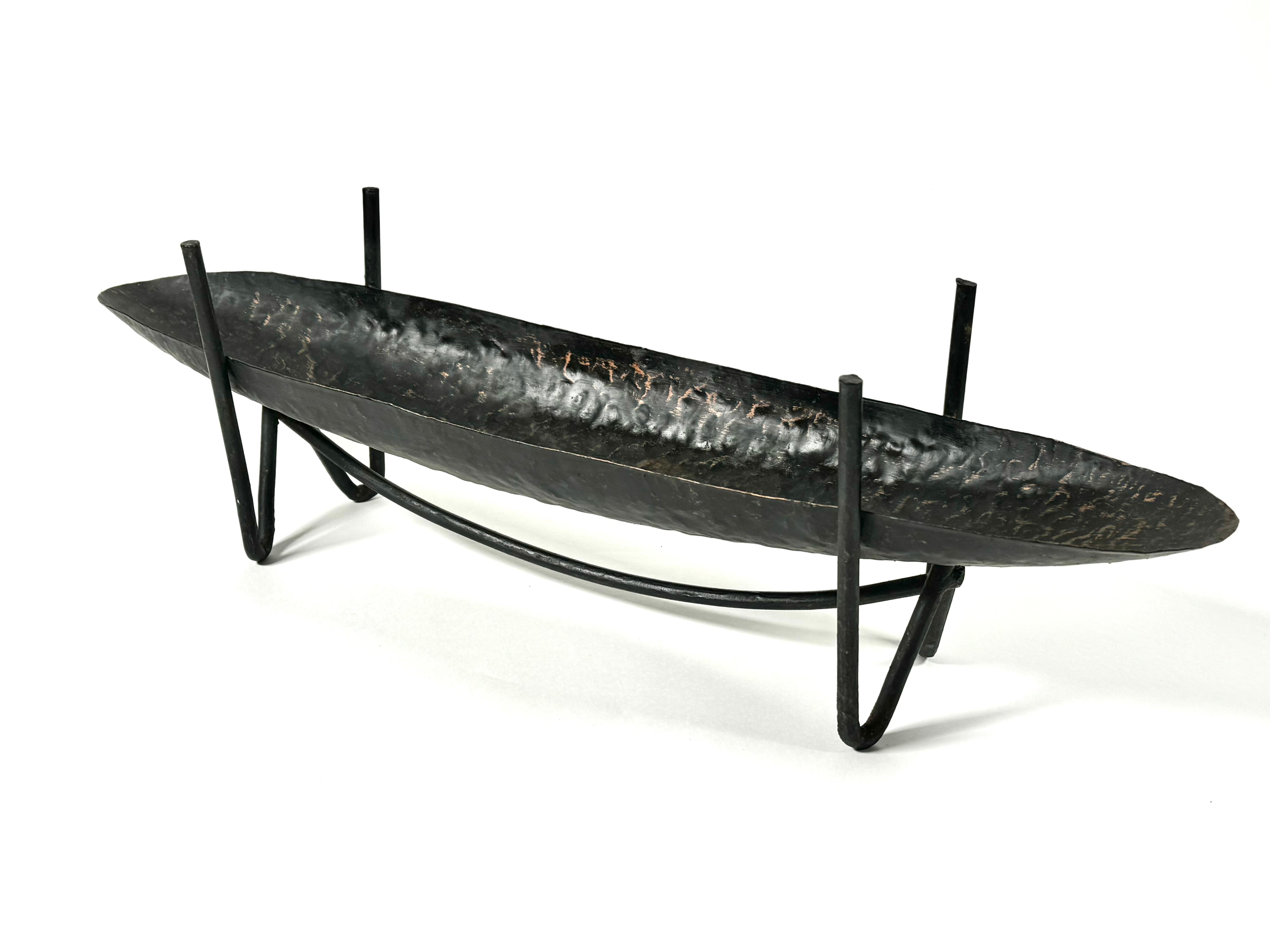 Purchased directly from Japan is this 1950s  modernist all metal ikebana vase, created out of hammered metal and welded wrought iron for the legs. The tray is an elongated narrow oval, the legs are a stylized hair pin with risers on the sides and a