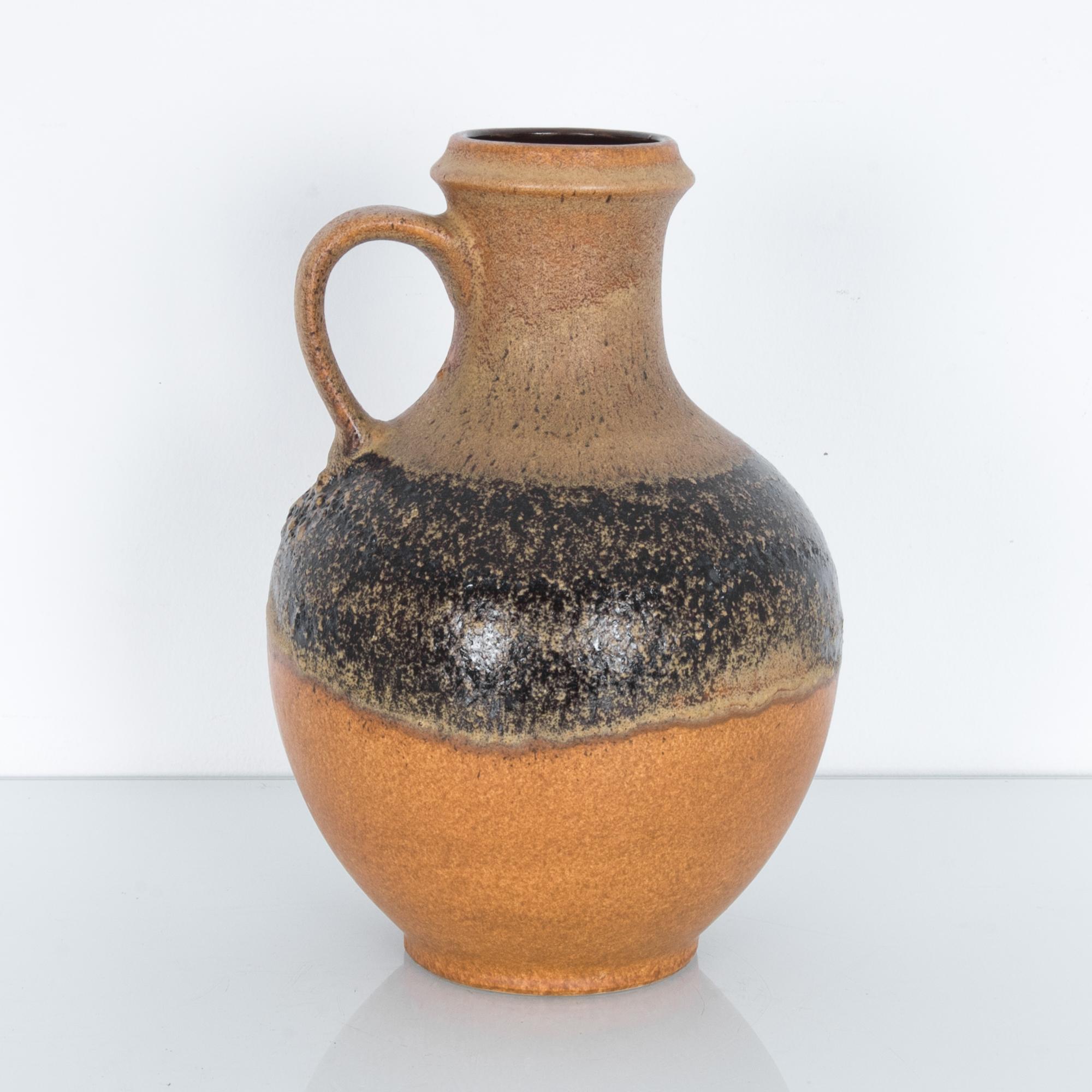 A ceramic vase produced in Germany, circa 1950. Glazed to highlight the natural texture of clay, a bold black stripe crosses a field of mottled orange. These characteristic mid-20th century ceramics were produced in West Germany, by a range of