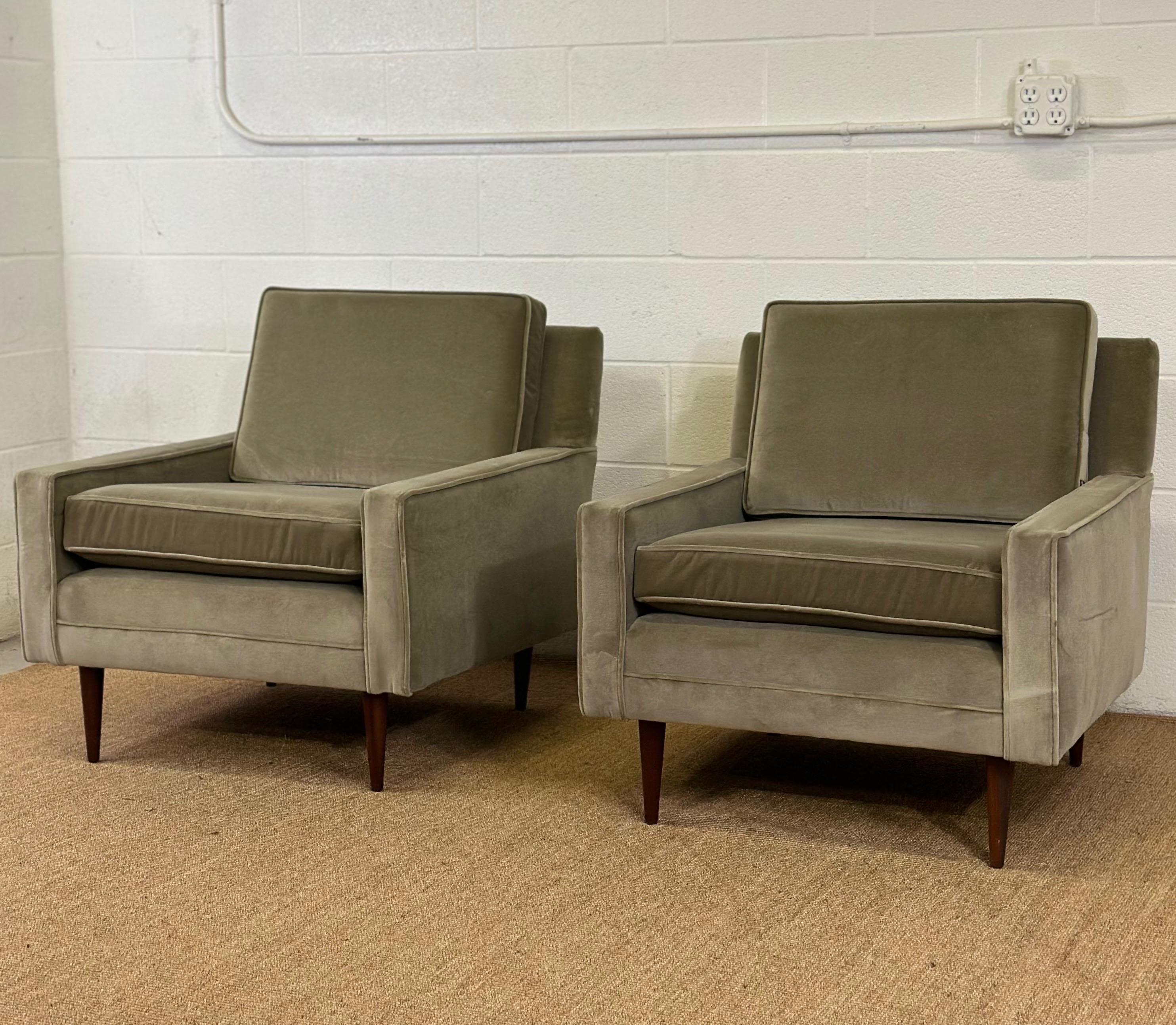 We are very pleased to offer a stunning vintage pair of Mid-Century Modern armchairs, circa the 1950s.  This set is distinguished by its remarkable linear silhouette and has been beautifully reupholstered to offer both style and comfort.  Each chair