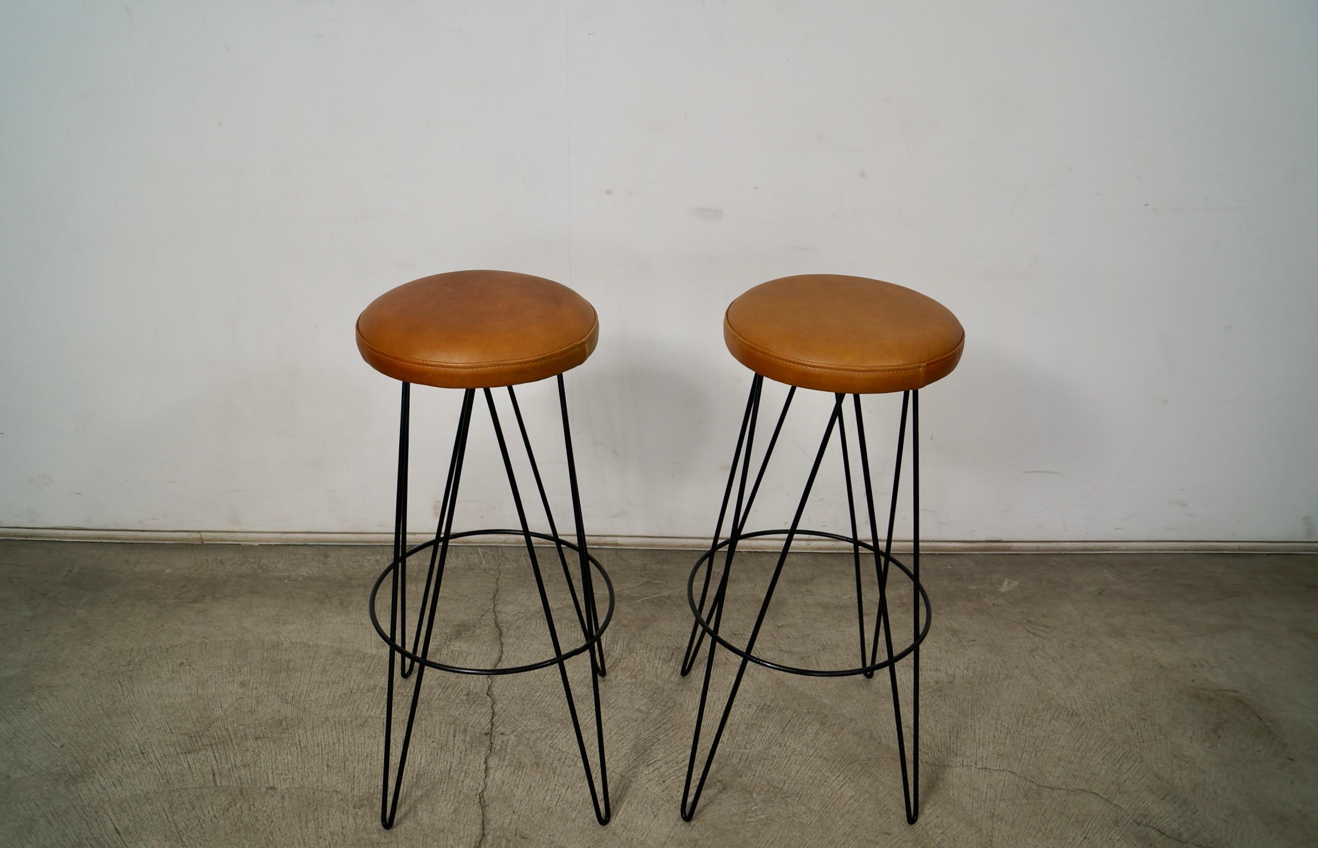 Coppia di sgabelli da bar Midcentury Modern originali in vendita. Risalgono agli anni '50 e hanno un design e uno stile molto classico. Hanno quattro gambe a forcina in ferro nero e sono state rivestite in pelle. La pelle è di colore marrone e