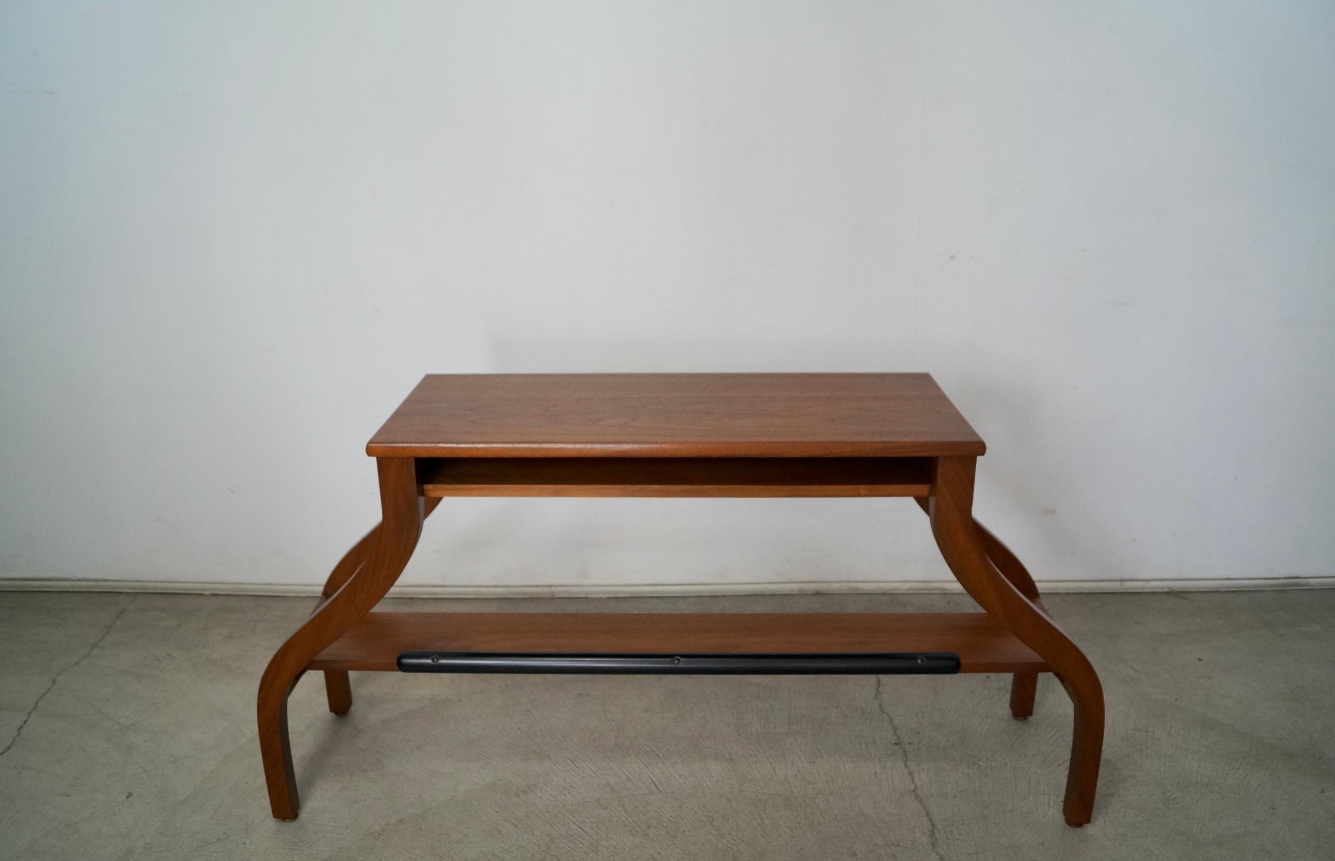 Vintage Midcentury Modern console table / shelf for sale. Made of walnut, and has been professionally refinished in a walnut finish. It has an unusual design and style with spider legs, and has a shelf underneath with a cubby hole. It can be used as