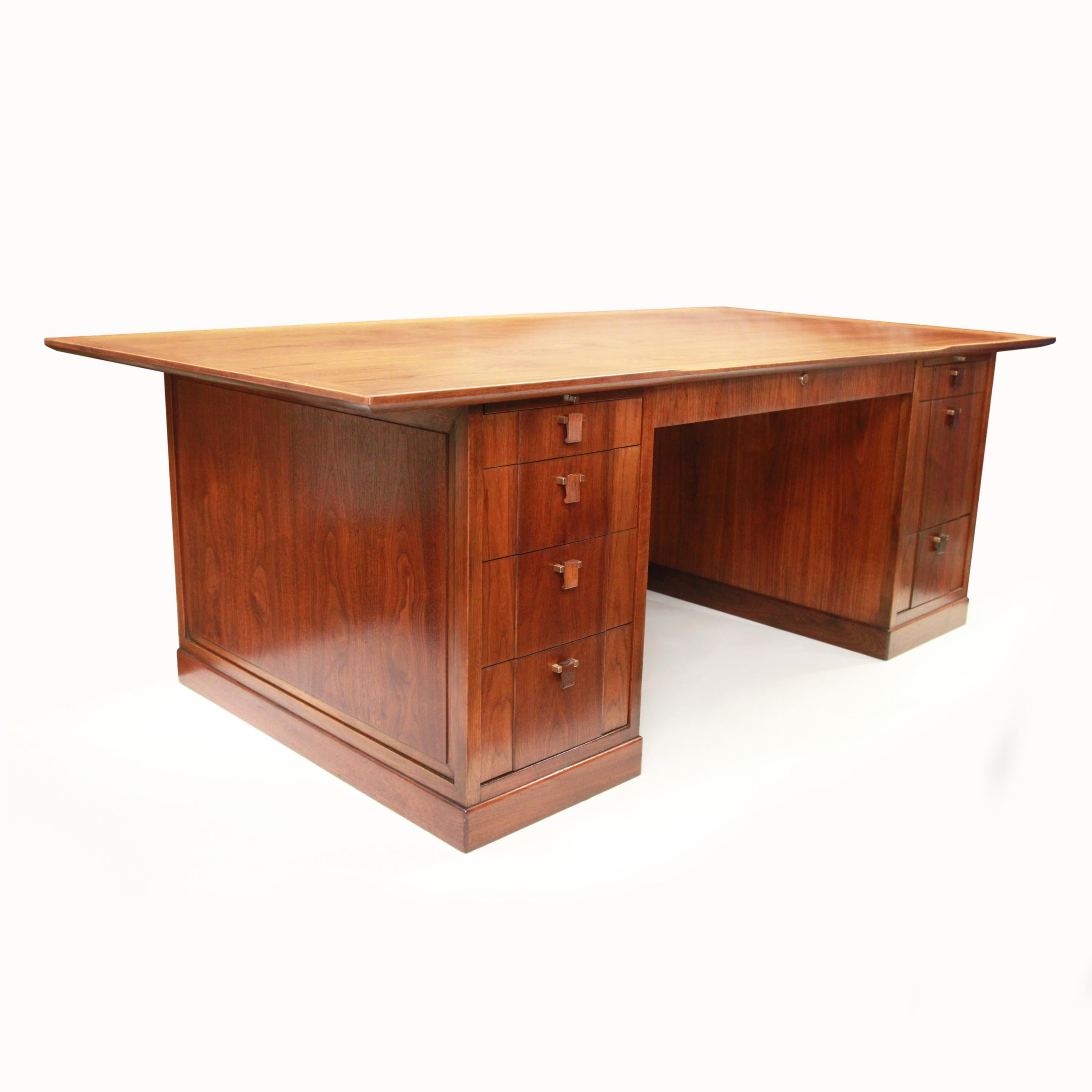 Grand style and grand scale combine in this wonderful executive desk by Edward Wormley for Dunbar. Desk features walnut construction, brass and mahogany pulls, and the renowned Dunbar build-quality. While the first thing you notice is the imposing