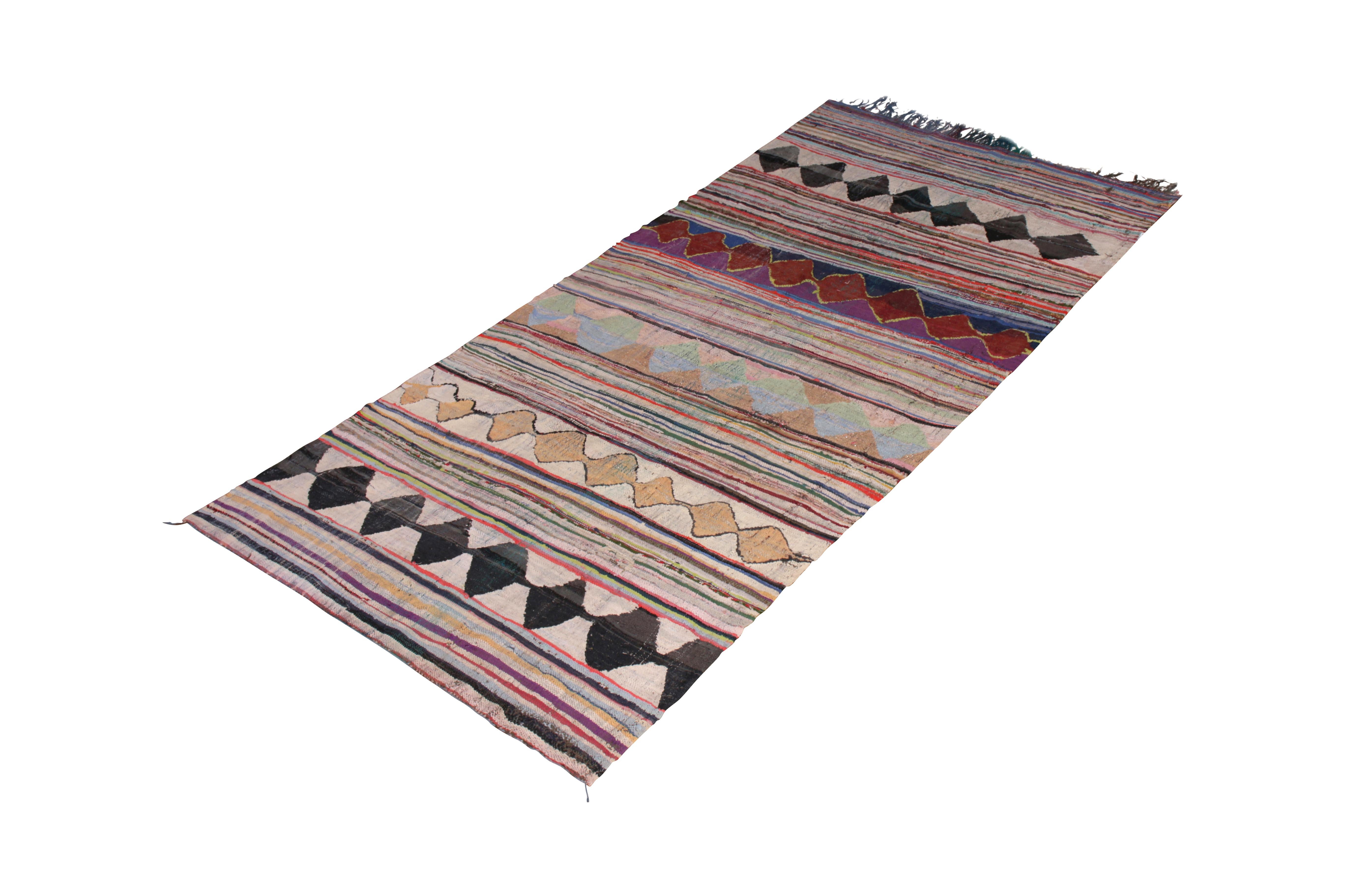 Hand knotted in Classic fabric originating from Morocco circa 1950-1960, this midcentury vintage Moroccan rug enjoys an ideal negotiation between bold patterns and joyful tones created through whimsical colorway; a juxtaposed play of a striped
