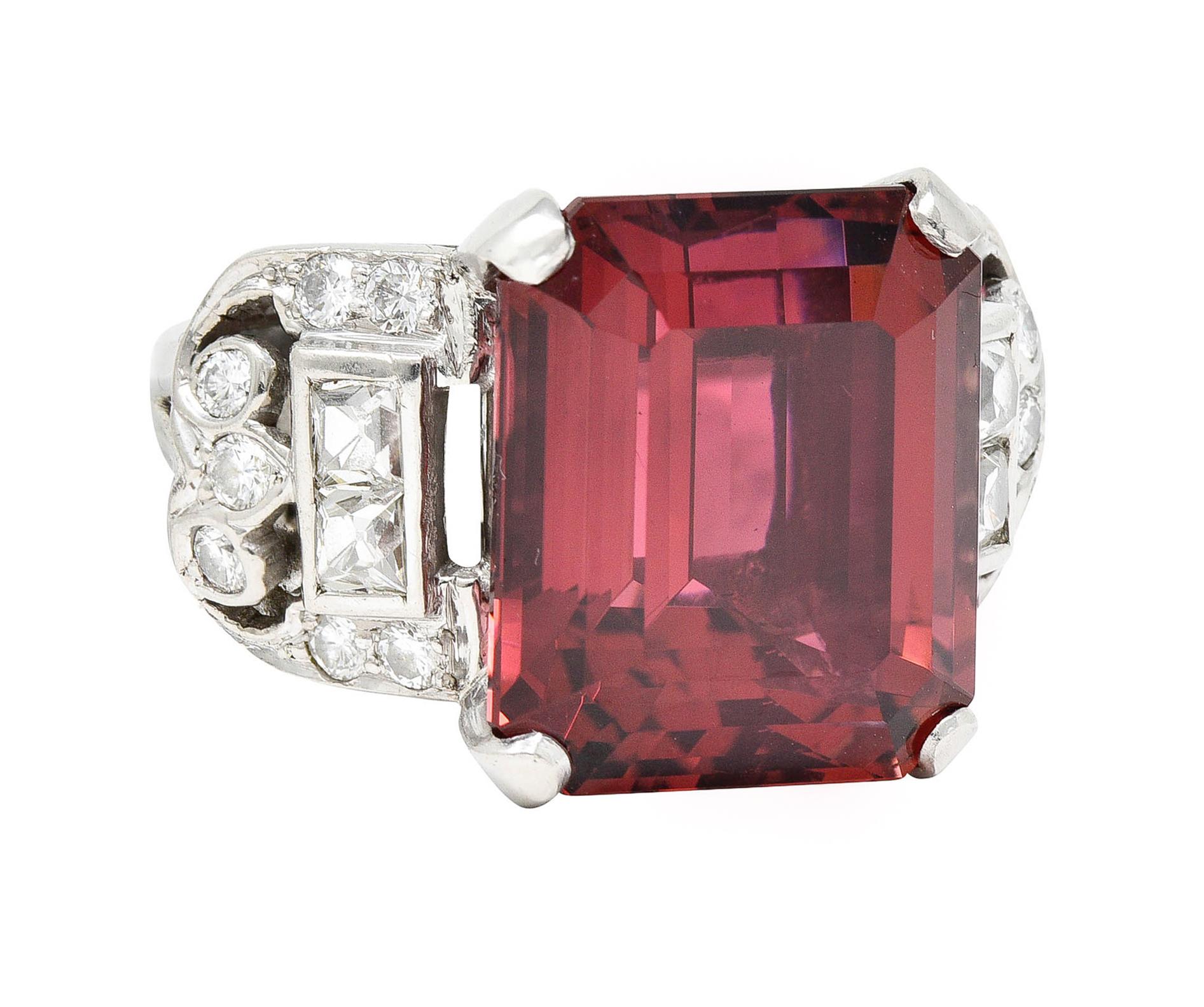 Featuring a substantial emerald cut rubellite tourmaline weighing 16.61 carats

Transparent with saturated violetish red color

Basket set by wide prongs and flanked by stylized ribbon-esque cathedral shoulders

With French cut and round brilliant