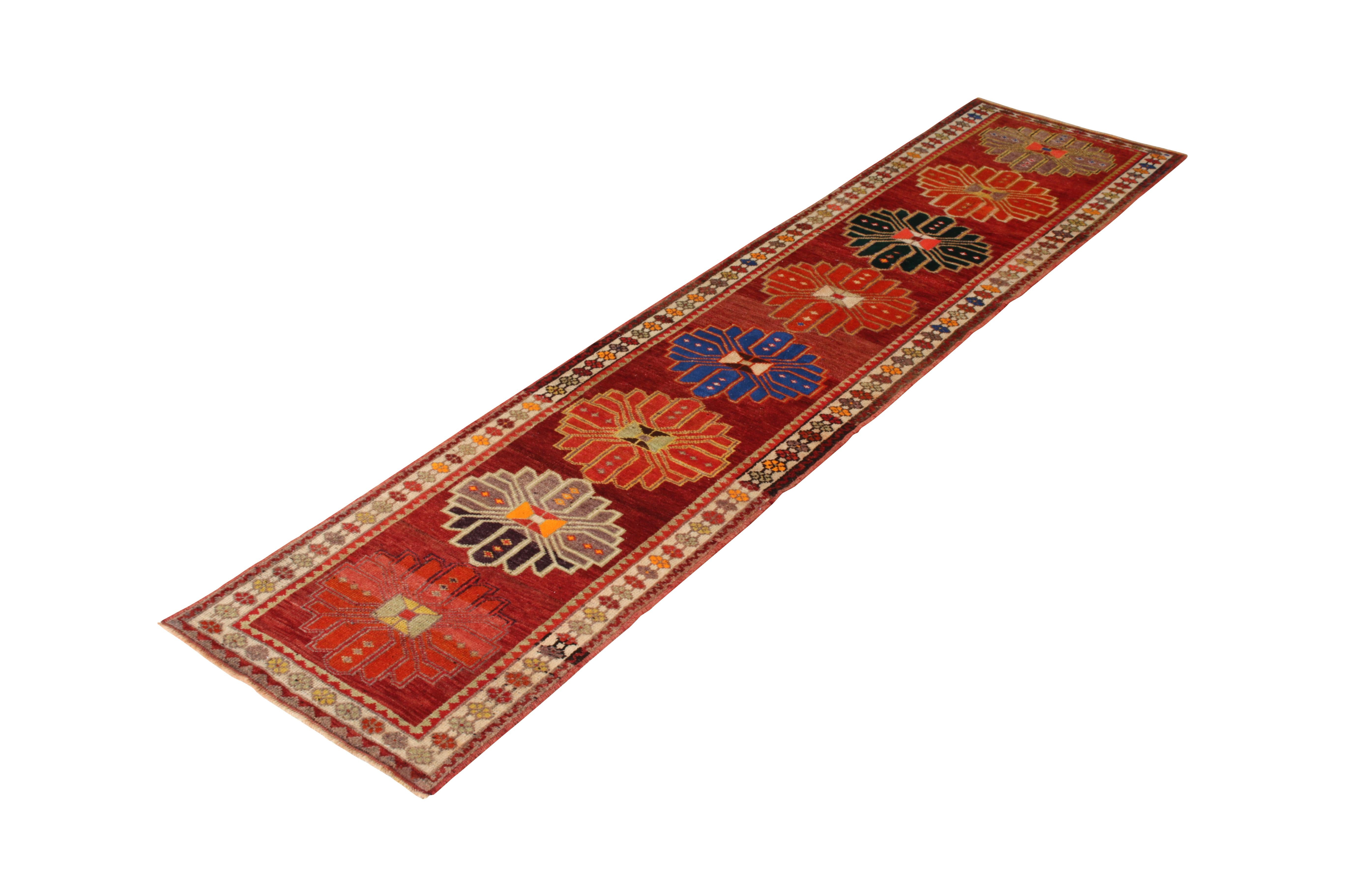 Hand knotted in wool originating from Turkey, circa 1950-1960, this vintage runner enjoys a distinctively rich, tastefully abrashed burgundy background, complemented by a series of arresting medallion patterns in the field. The variations of