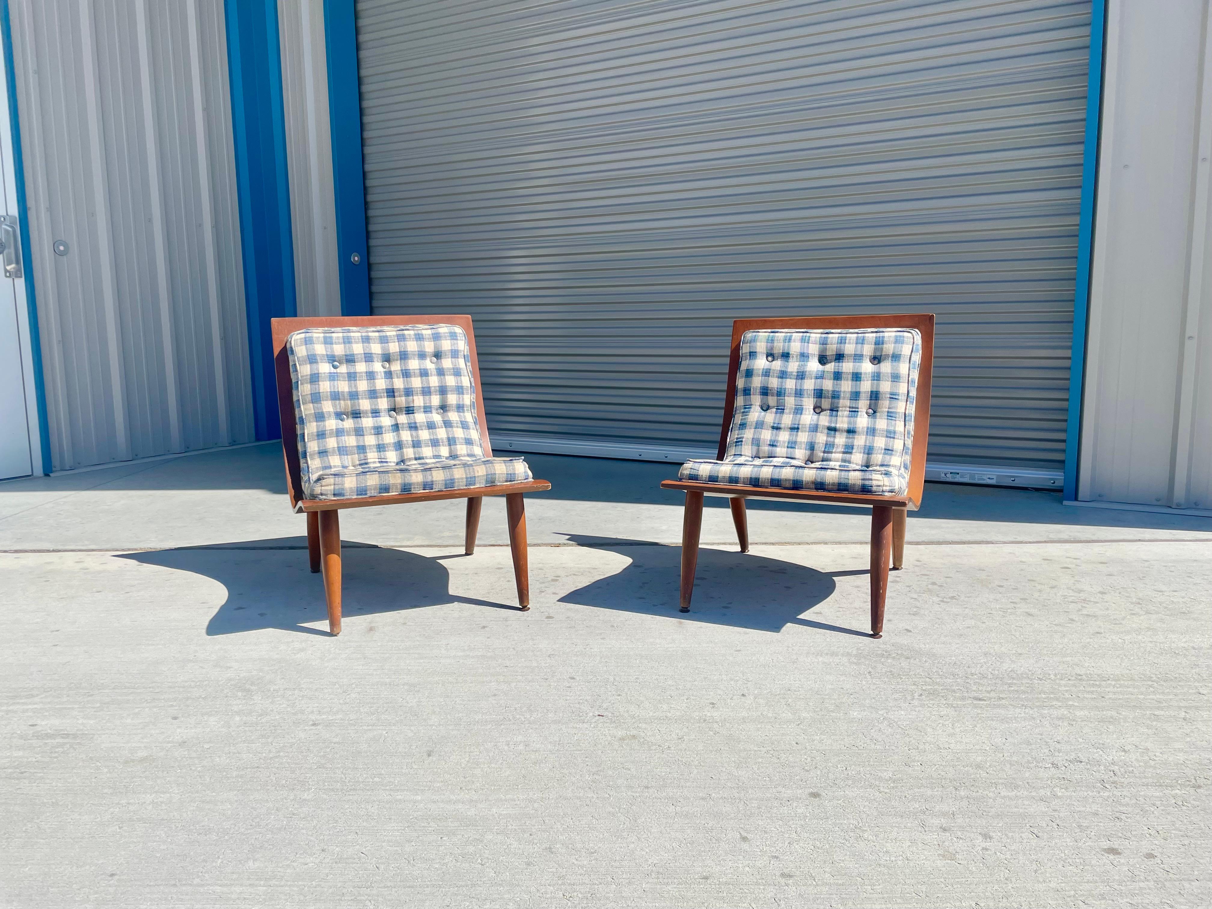 Vintage scoop lounge chairs manufactured by Carter Brothers, circa the 1950s. This midcentury pair of scoop chairs feature a sleek design covered in blue and white pattern upholstery with a walnut back. The chairs also have a unique wave shape