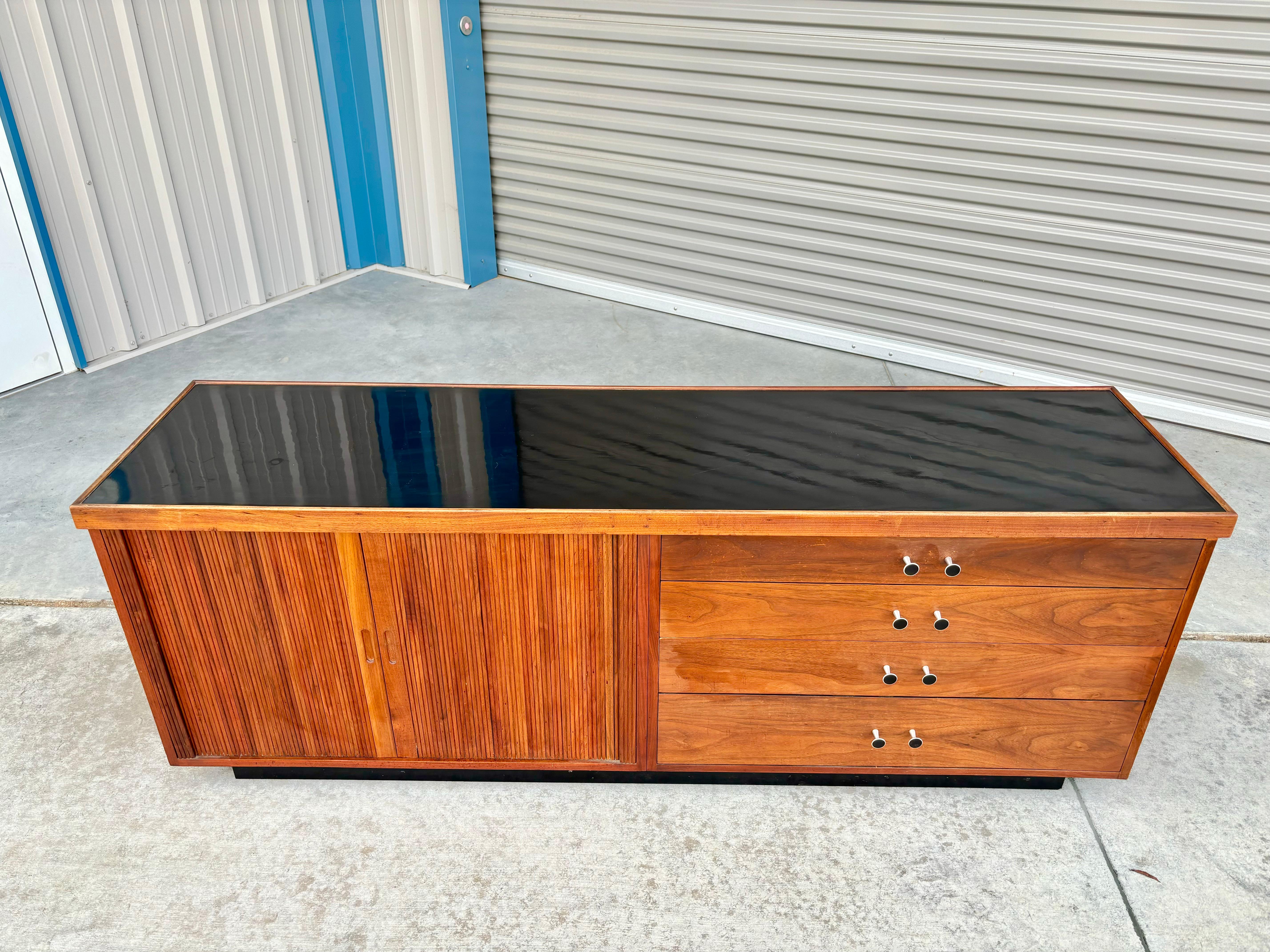 Mid-century walnut tambour door credenza was designed and manufactured by Glenn of California in the United States circa 1950s. This stunning piece features a beautiful walnut frame that exudes elegance and sophistication. The credenza boasts four