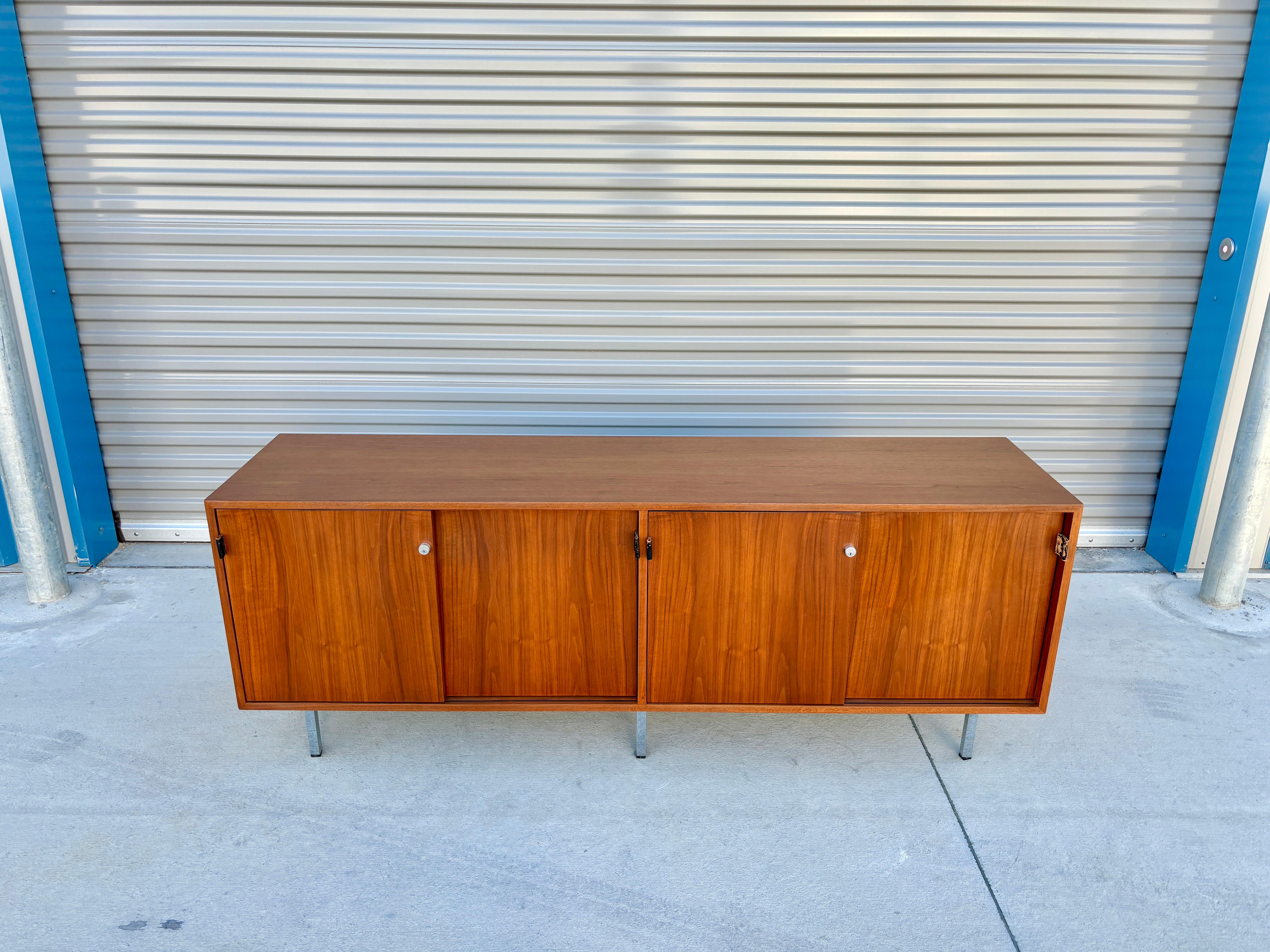 Crédence en noyer du milieu du siècle conçue par Florence Knoll et fabriquée par Knoll Associates Inc. vers les années 1950. Cette pièce exceptionnelle présente un superbe cadre en noyer soutenu par quatre pieds chromés. Ses portes coulissantes en