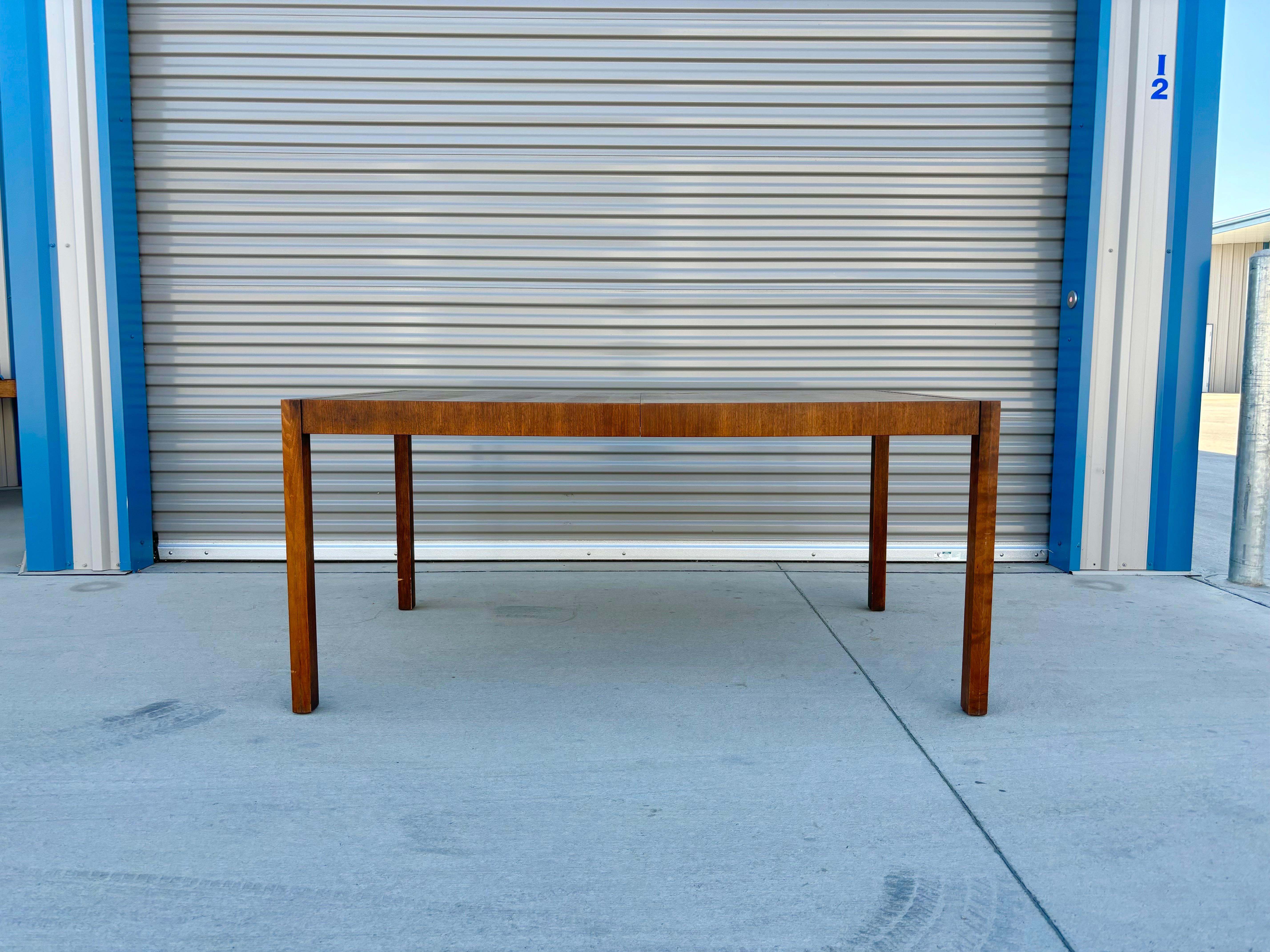 Mid-century dining table that was designed and manufactured in the United States circa 1950s. The table is made from a beautiful walnut frame and has two leaves that can be added to make the table longer. It's a true beauty and will surely add a
