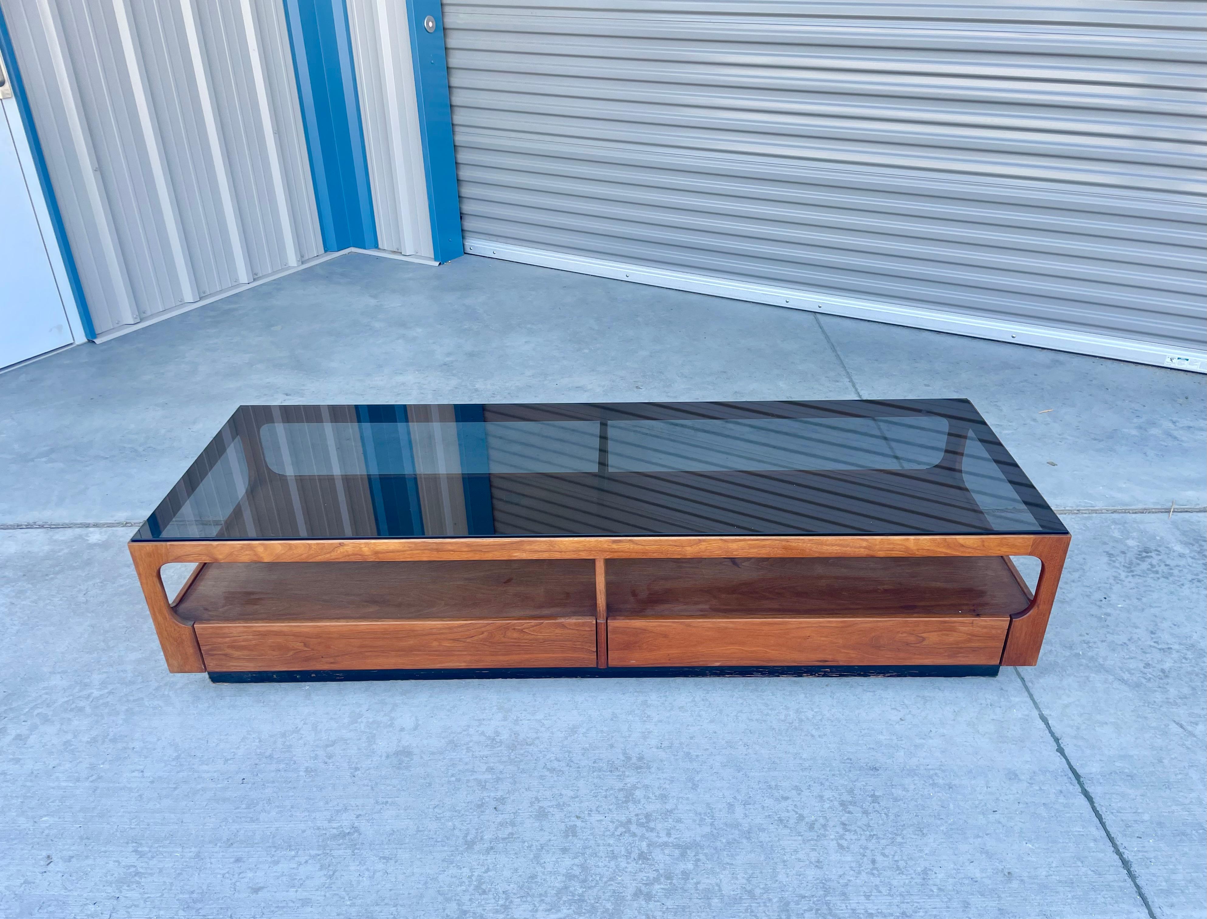 Mid-century walnut & glass coffee table designed by John Keal and manufactured by Brown Saltman in the United States circa 1950s. This stunning coffee table features a smoke glass top that sits on a rectangular walnut frame. The coffee table also