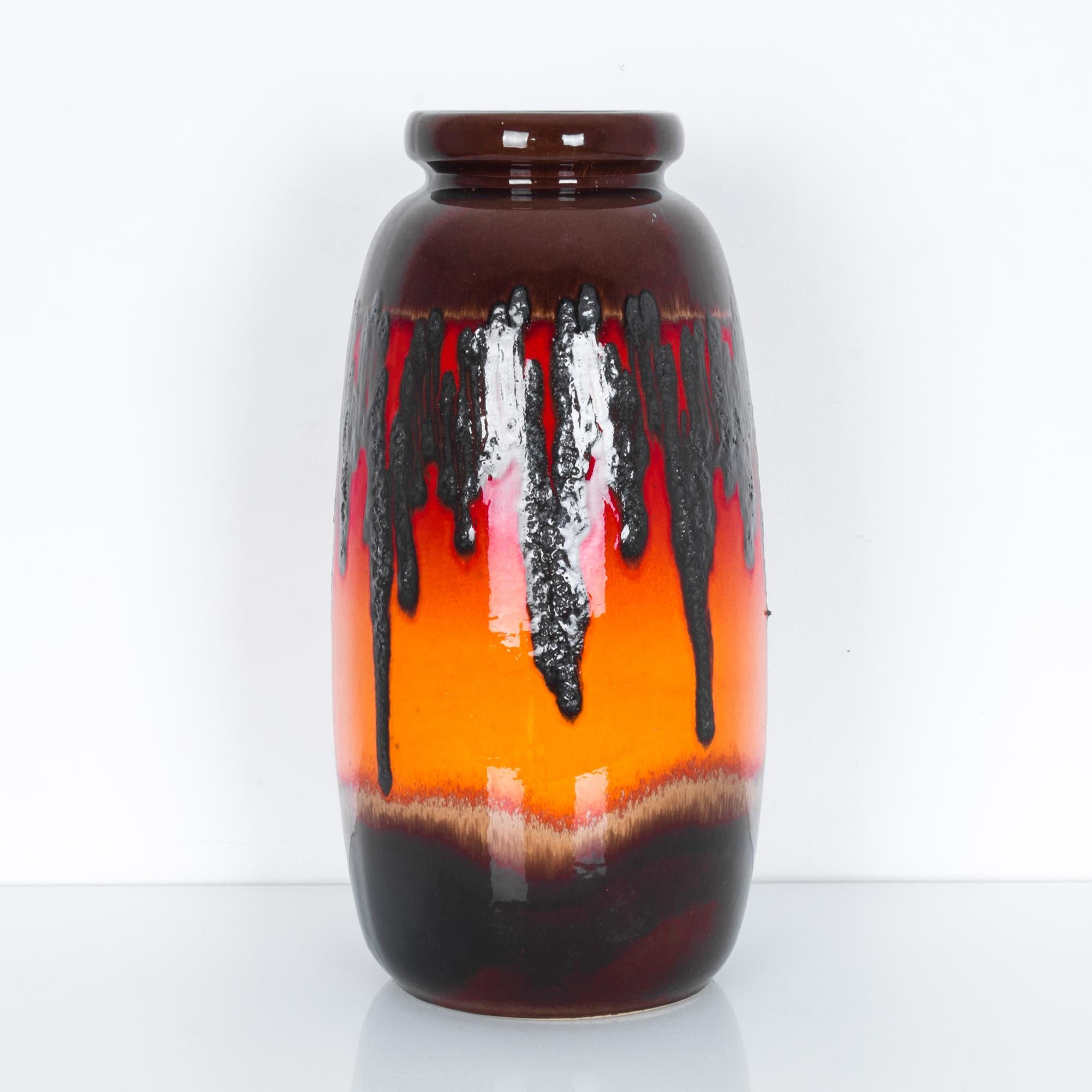 A ceramic vase from West Germany, circa 1950. An elegant and simple form allows the bold color composition to shine. A rich brown melds into striking oranges and reds, scored through with an abstract graphic scribble. Modernist and striking, yet
