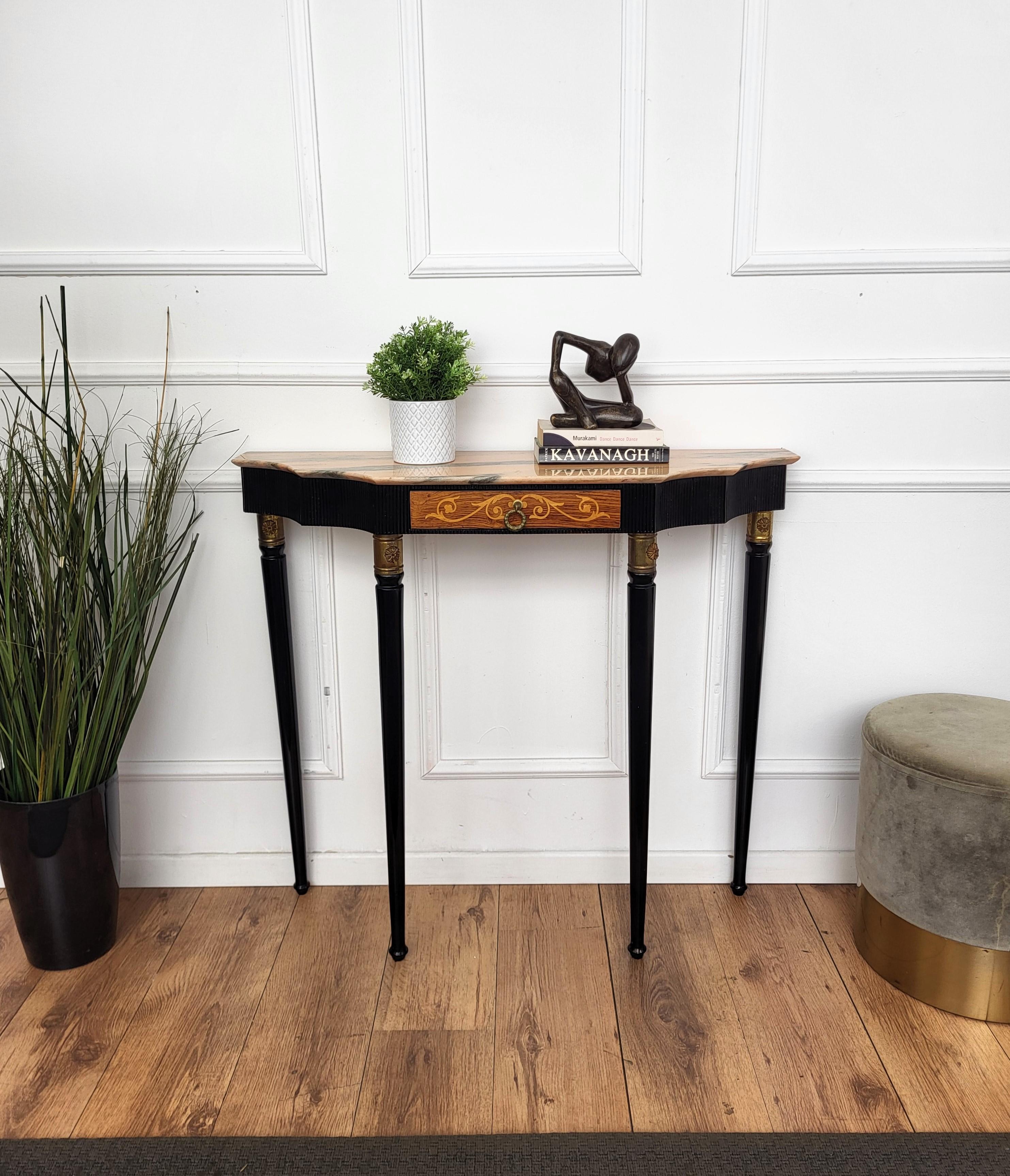 Very elegant and refined Italian 1950s Mid-Century Modern and neoclassical design console table highlighted by the slatted workmanship of the wooden top part and the decorated central drawer. The four elegantly shaped legs decorated with brass