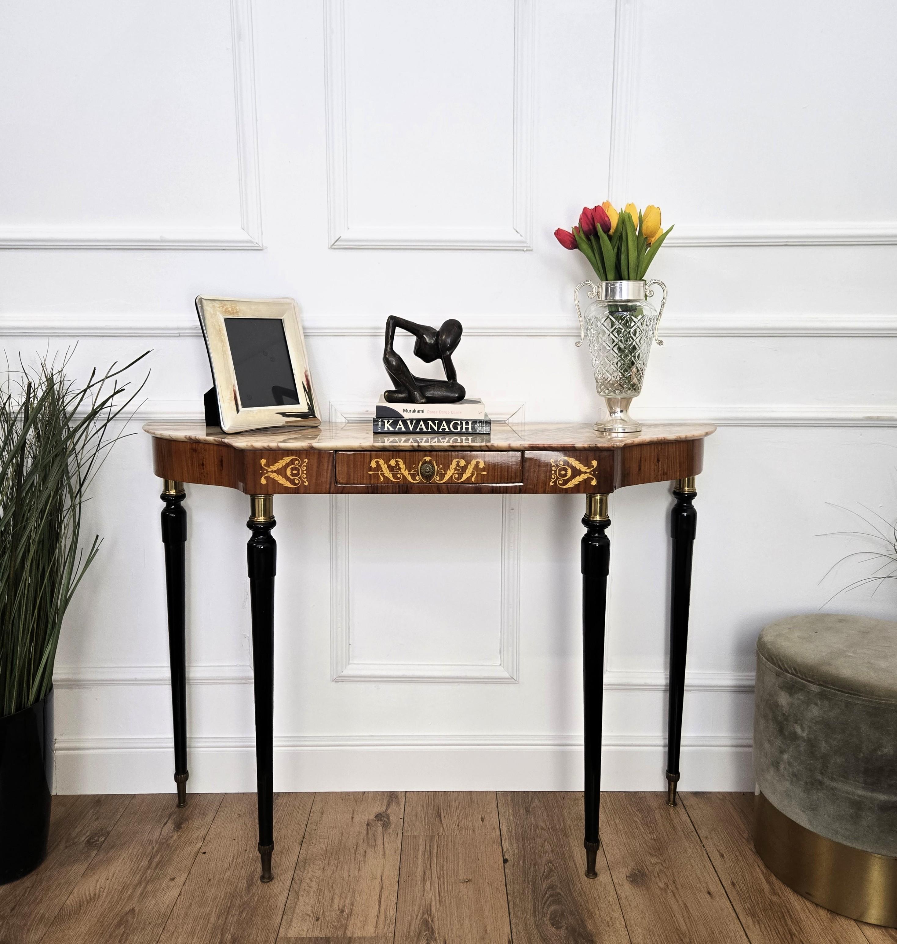 Very elegant and refined Italian 1950s Mid-Century Modern and neoclassical design console table highlighted by the great workmanship of the wooden part and the decorated central drawer. The four elegantly shaped legs decorated with brass details and