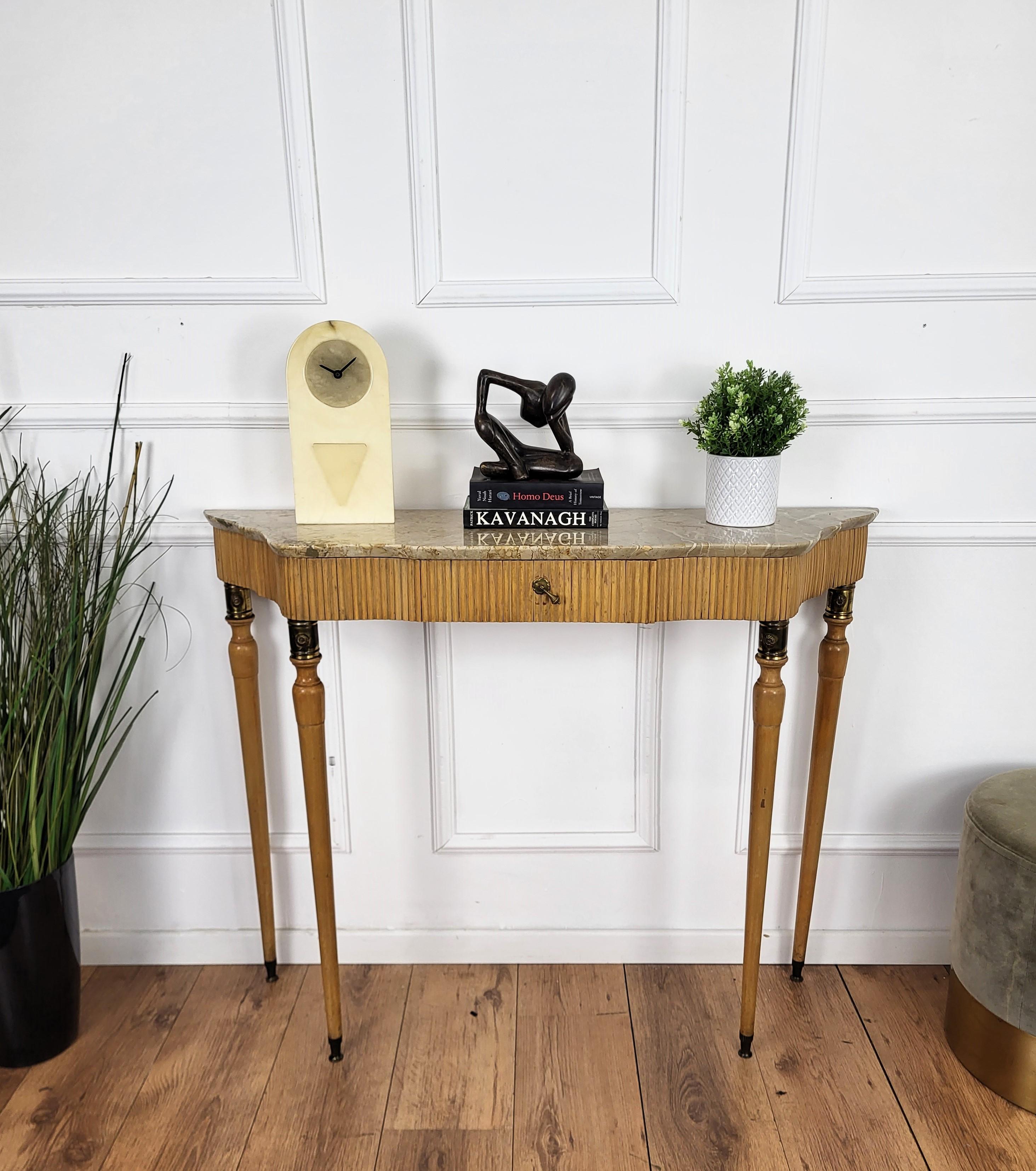 Very elegant and refined Italian 1950s Mid-Century Modern and neoclassical design console table highlighted by the slatted workmanship of the wooden top part and drawer. The four elegantly shaped legs decorated with brass details and with its
