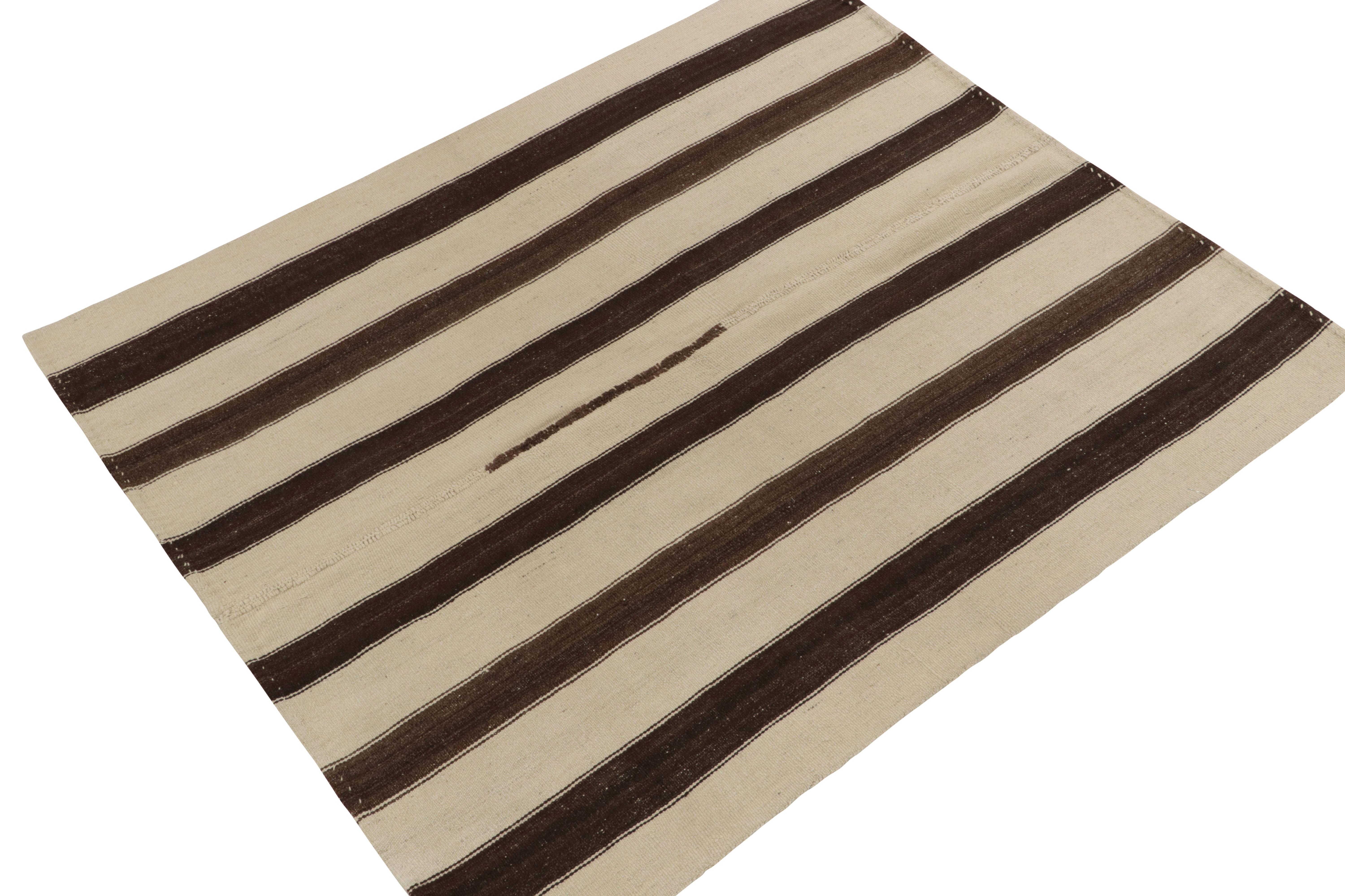 Un tapis kilim vintage 5x6 de nos sélections de tissage plat, originaire de Turquie vers 1960-1970. Tissé à la main en laine, ce tapis présente un style distinctif de panneau tissé jouant des rayures beiges et brunes avec un attrait neutre très