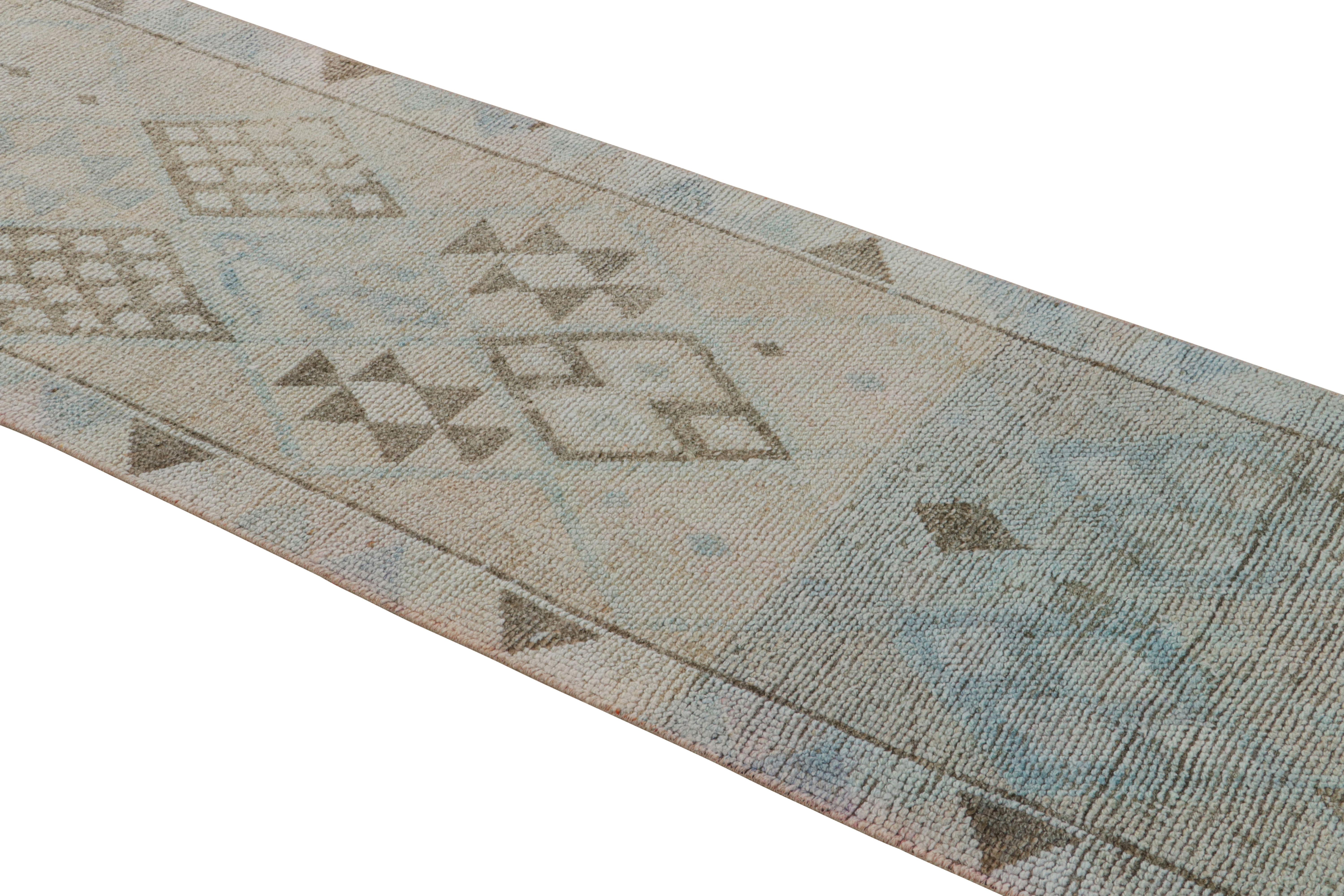 Hand knotted in wool originating from Turkey circa 1950-1960, this vintage wool runner enjoys a rare off-white colorway complementing the geometric variations of beige-brown and blue patterns with a bright, versatile allure. The pile height in this