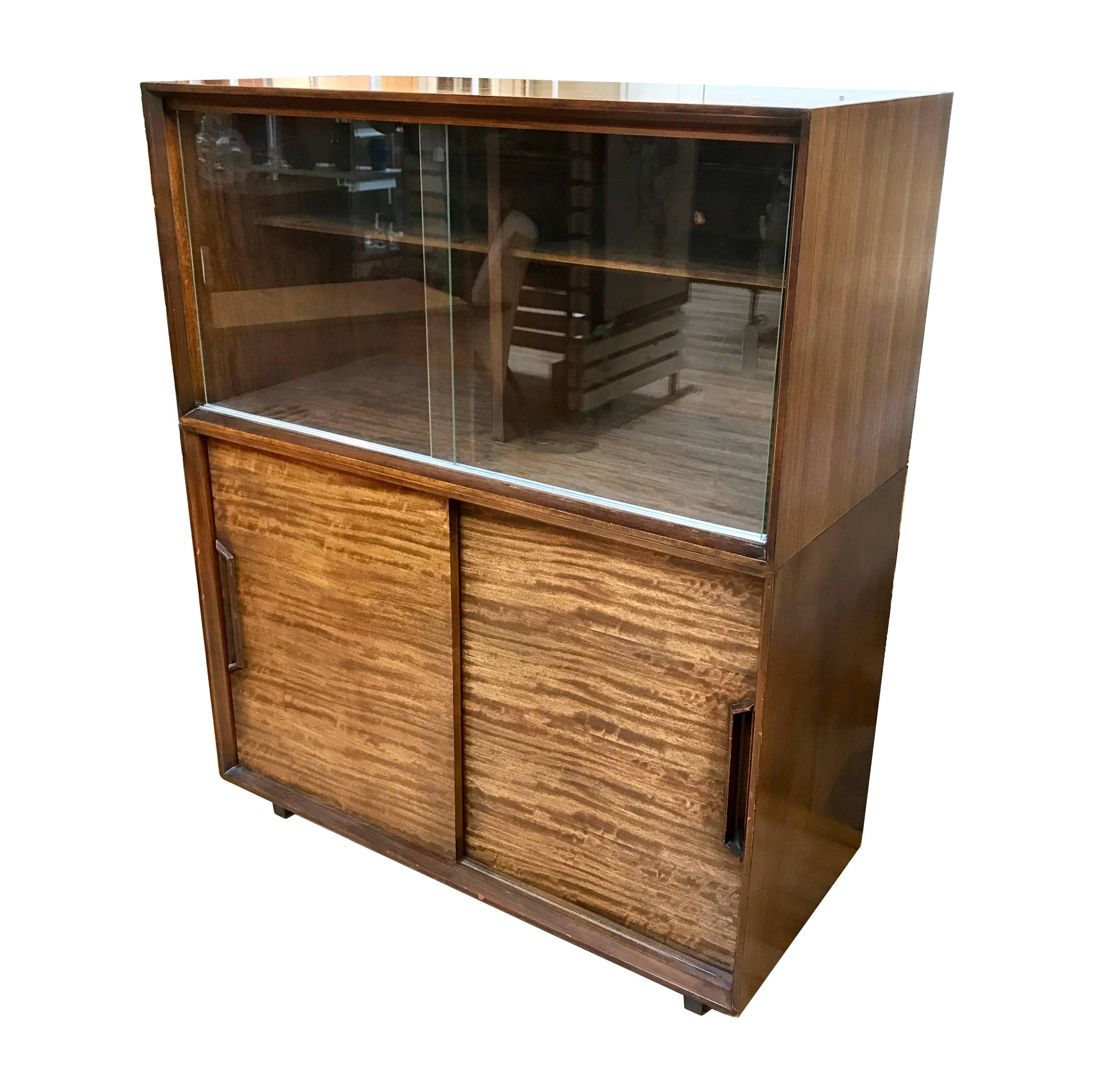 1950s China hutch designed by Milo Baughman for Drexel Perspective. Made of Mindoro wood, the hutch has two sliding glass doors and adjustable shelves in the upper section, and two sliding wood doors with drawers and adjustable shelving in the lower
