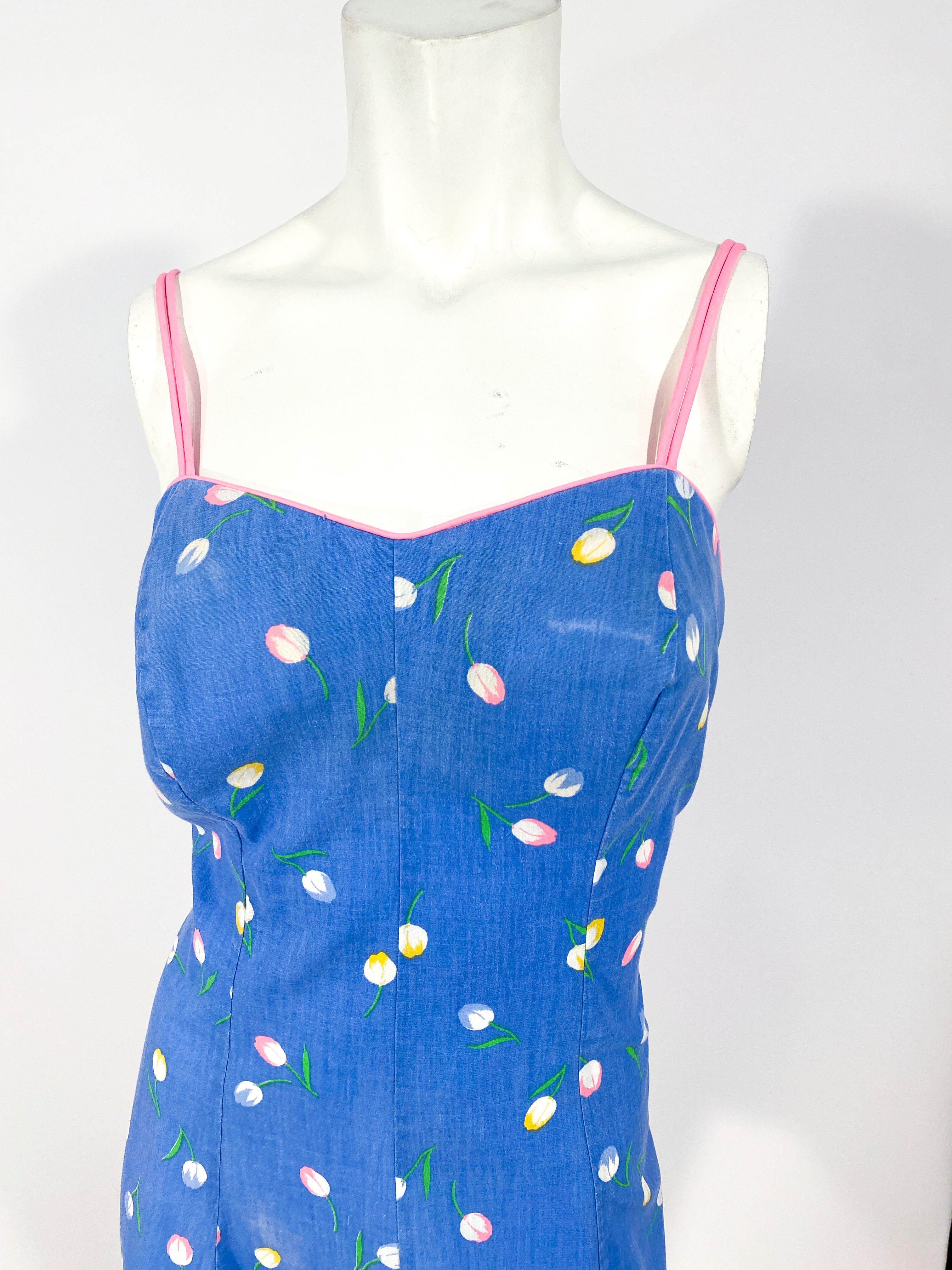 1950s mini sun dress featuring a pink and yellow tulip print on a periwinkle background. The structured bodice is timed in a hot pink piping and the torso is ruched for comfort and give.