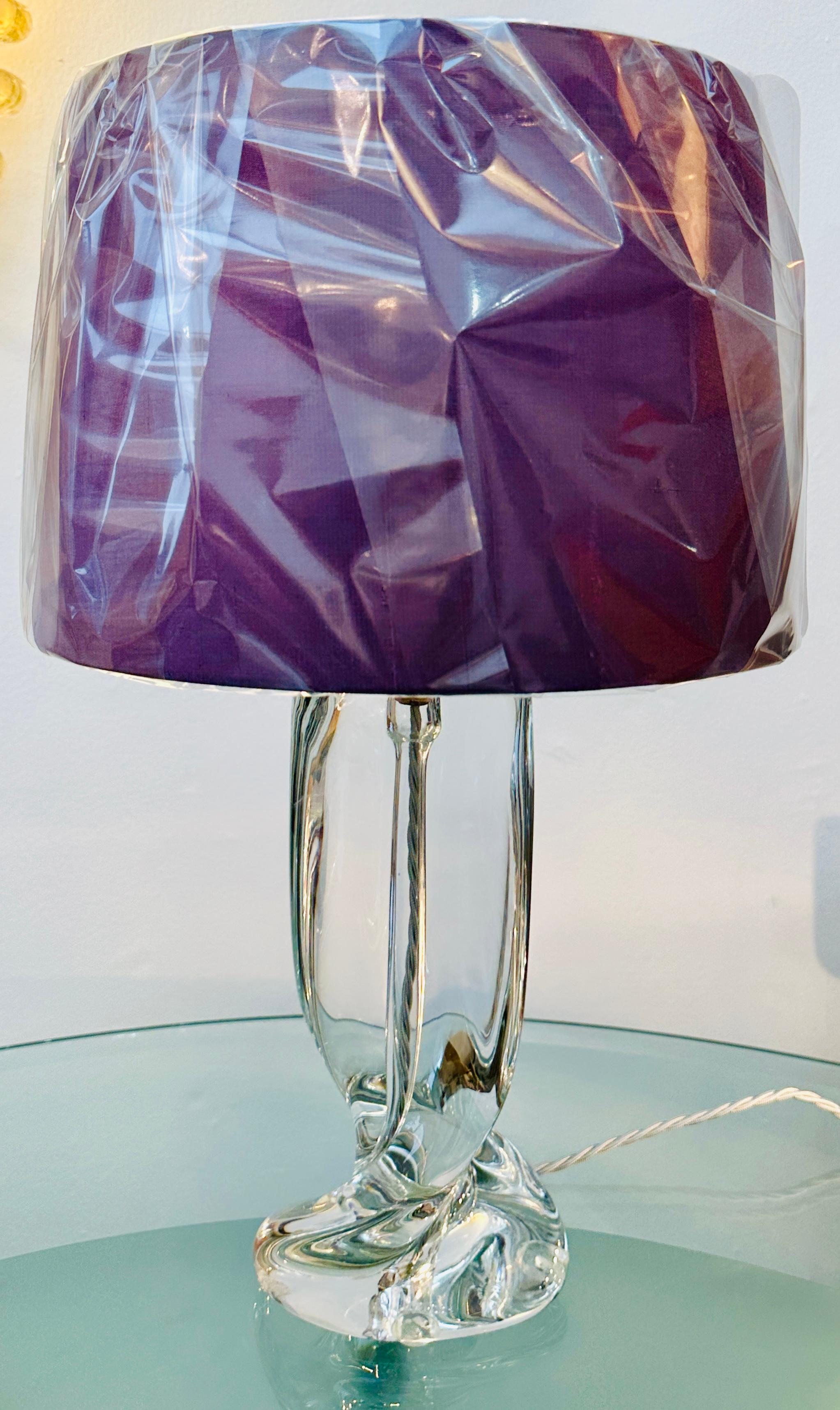 An elegant, sculptural, solid crystal glass table lamp manufactured by the famous French glassmaker Cristalleries De Sèvres. The lamp features a sculptural clear solid glass body which twists towards the base.  The silver twisted silk flex runs