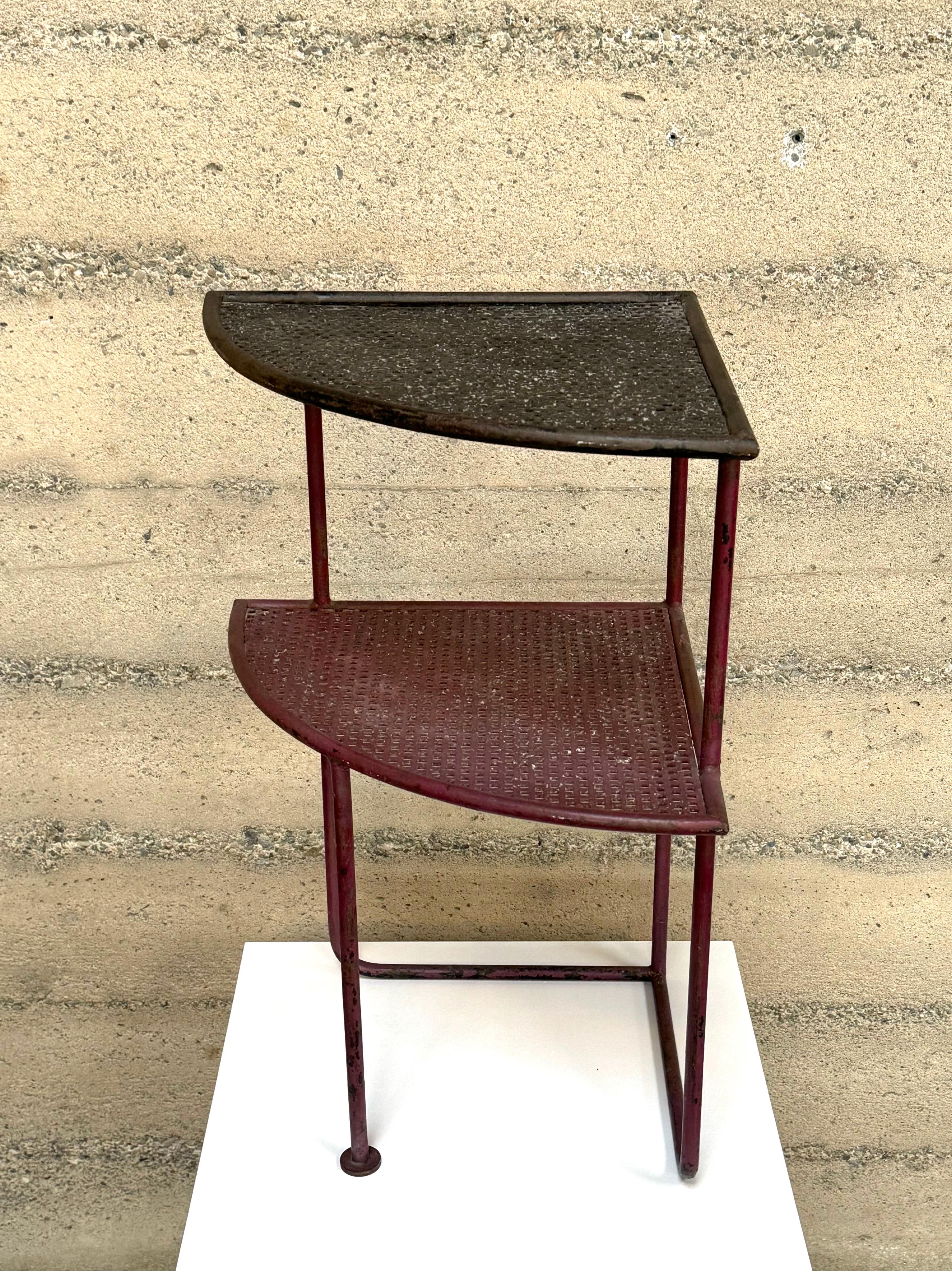 Triangular perforated metal side table in the style of Mathieu Mategot, all original condition with a soft red and black finish, there is a distinctive patina to the finish giving it a rich character. The table has two shelves of equal size with a