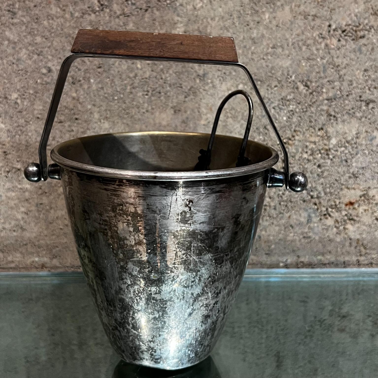 1950s Modernist silver plate ice bucket set with sculptural tongs
Vintage ice bucket, silver plated with original vintage patina.
Wood block (possibly mahogany) to add contrast to the modernist clean lines.
Includes vintage ice tongs, Tongs