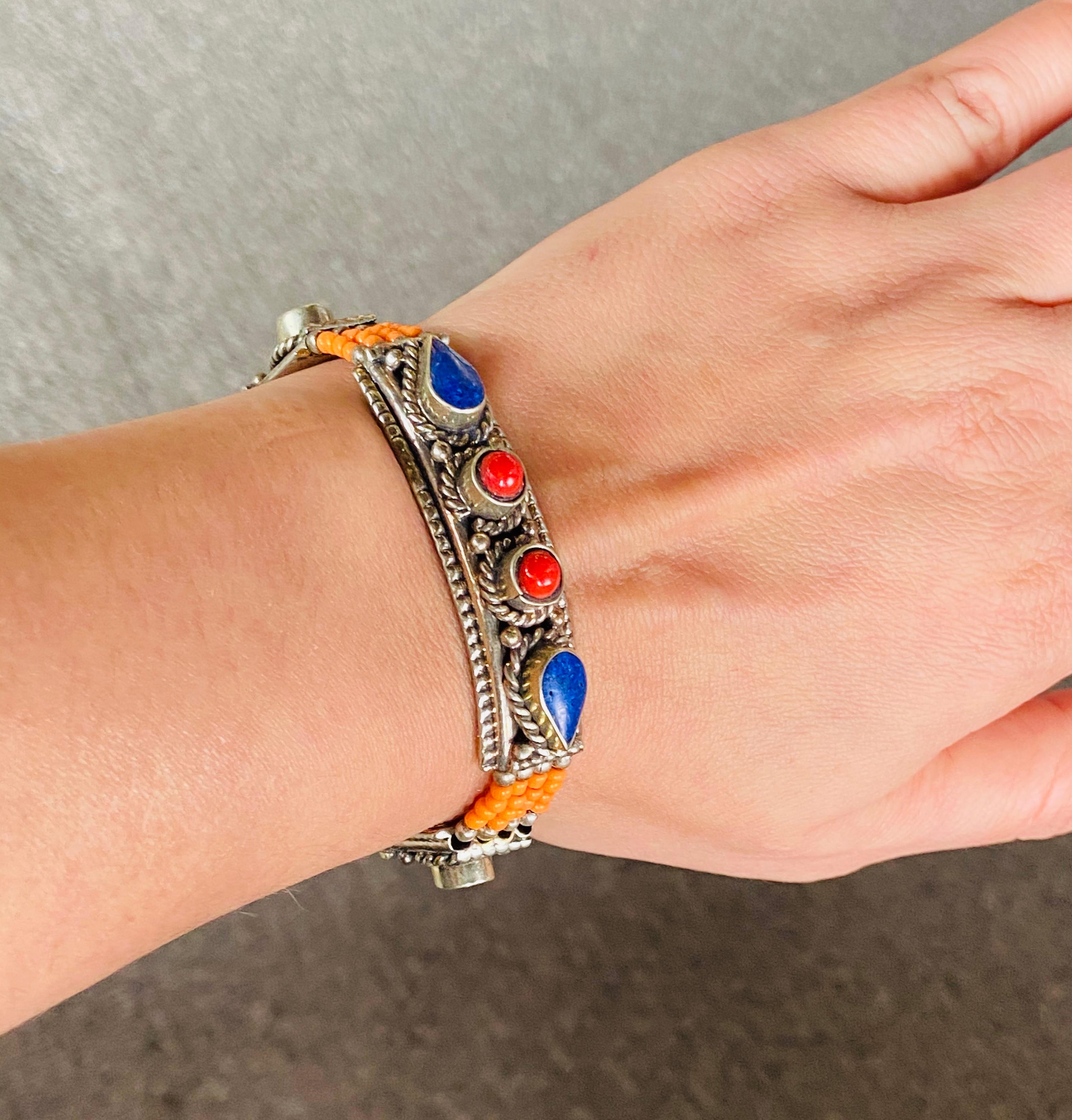 A stunning handmade Moroccan Berber tribal pure silver bracelet. This beautiful and one of a kind piece of jewelry made around 1950's in the Atlas Mountains in Morocco features Red , blue and orange colors and genuine natural. The impressive