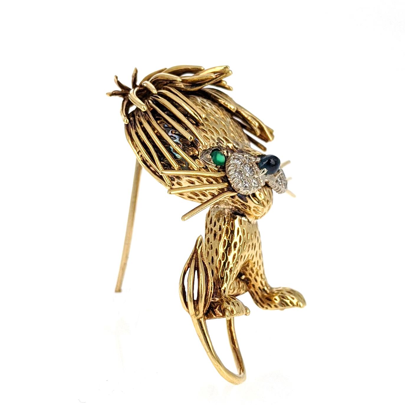 This cute lion brooch is expertly crafted in 18 karat yellow gold and features a sapphire cabochon nose accented by twelve single-cut diamonds and two round emerald eyes. It is marked 18K KIRI. Measures approximately 1.75 inches tall. 

This little