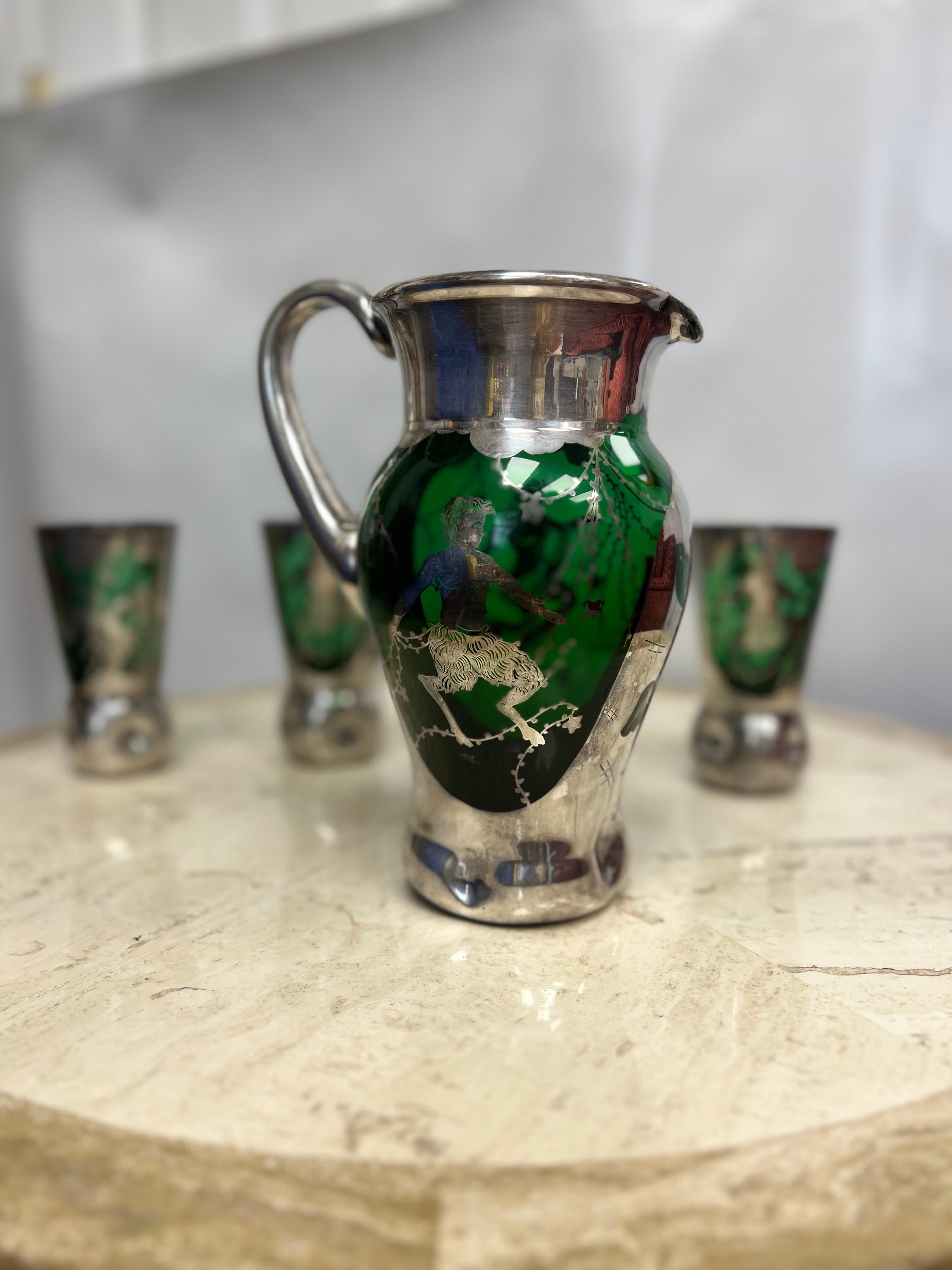 Fabulous set of three Murano green drinking glasses and pitcher with silver overlay. Each glass and matching pitcher is decorated with the rare design of a dancing satyr and forest nymph. This stunning set has dimpled bases. A very decorative set
