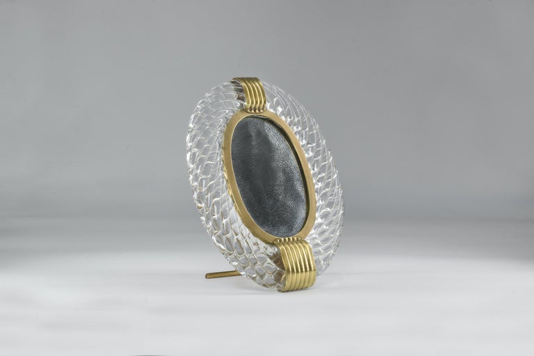 A beautiful midcentury photo frame crafted by Venini and designed by Carlo Scarpa, circa 1950s. The hand-blown transparent twisted Torchon style Murano glass frame and luxurious brass details emphasize this beautiful oval-shaped decorative piece.