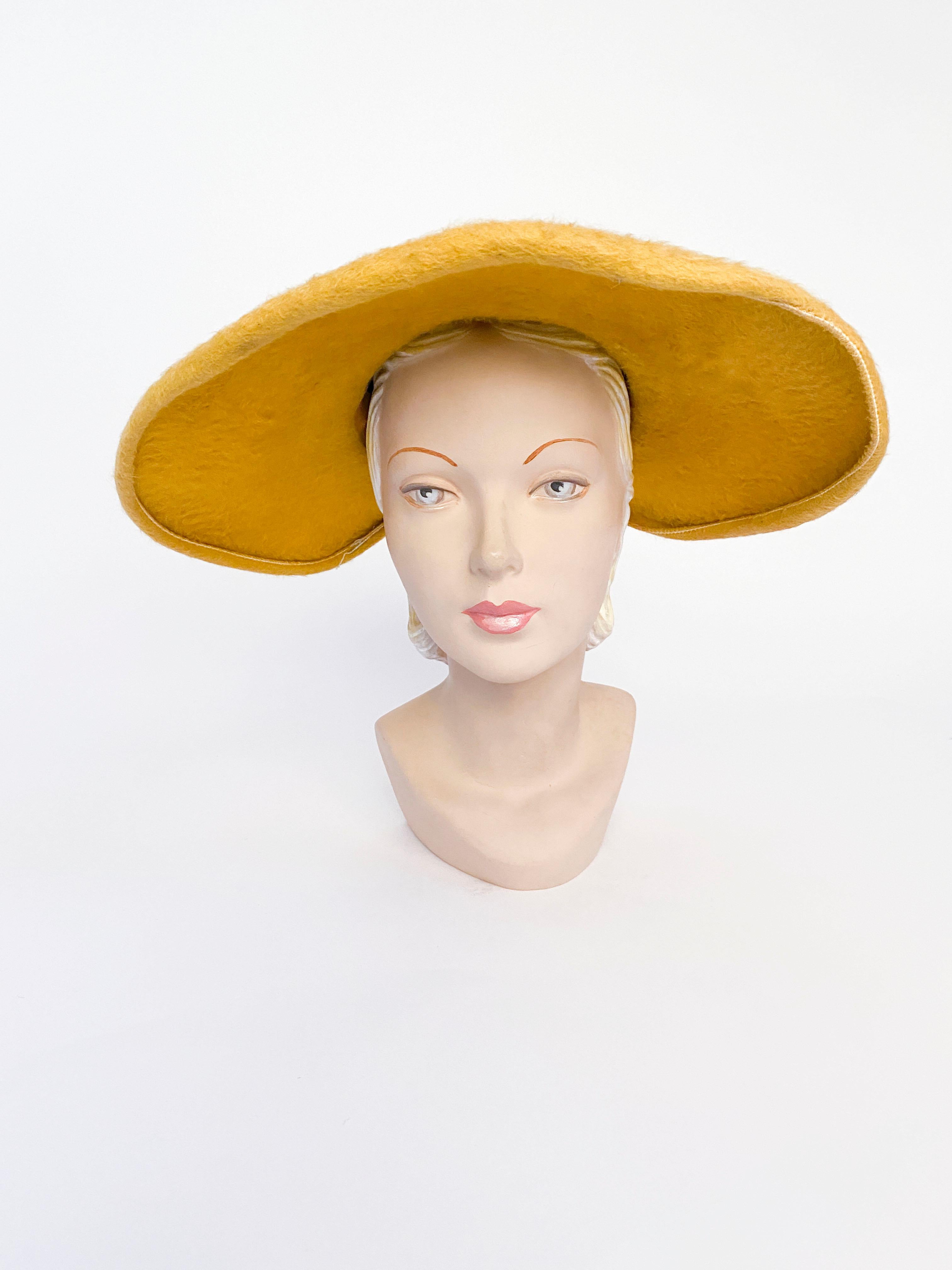 1950s mustard yellow beaver fur felt hat finished with a handmade cord and pearl hat band that ends to a decorative bow and tails extending over the wide brim. The brim is fully wired and there is an inner attached elastic hat band worn on the back