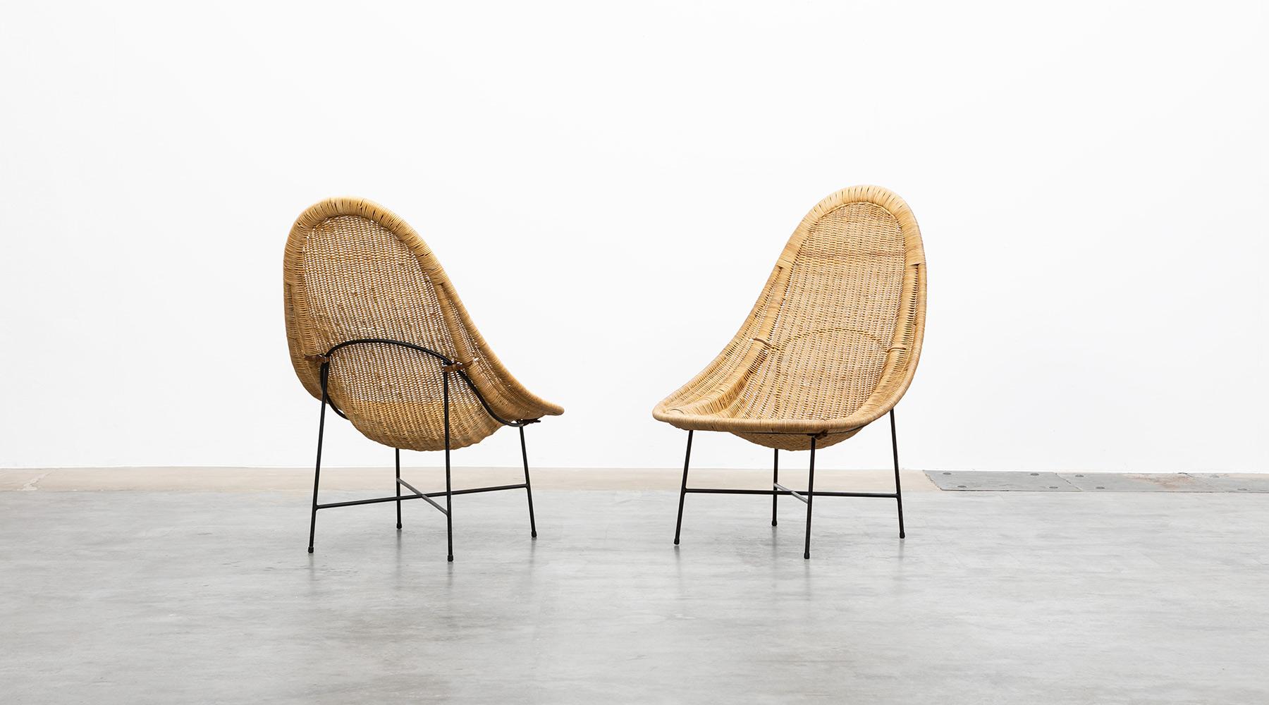 Kerstin Holmquist lounge chairs by Nordiska Kompaniets Verkstäder, Sweden, 1950.

The beautifully crafted basket shells lies elegantly on the black lacquered metal frame, held in place only by two leather straps at the back side. The seating