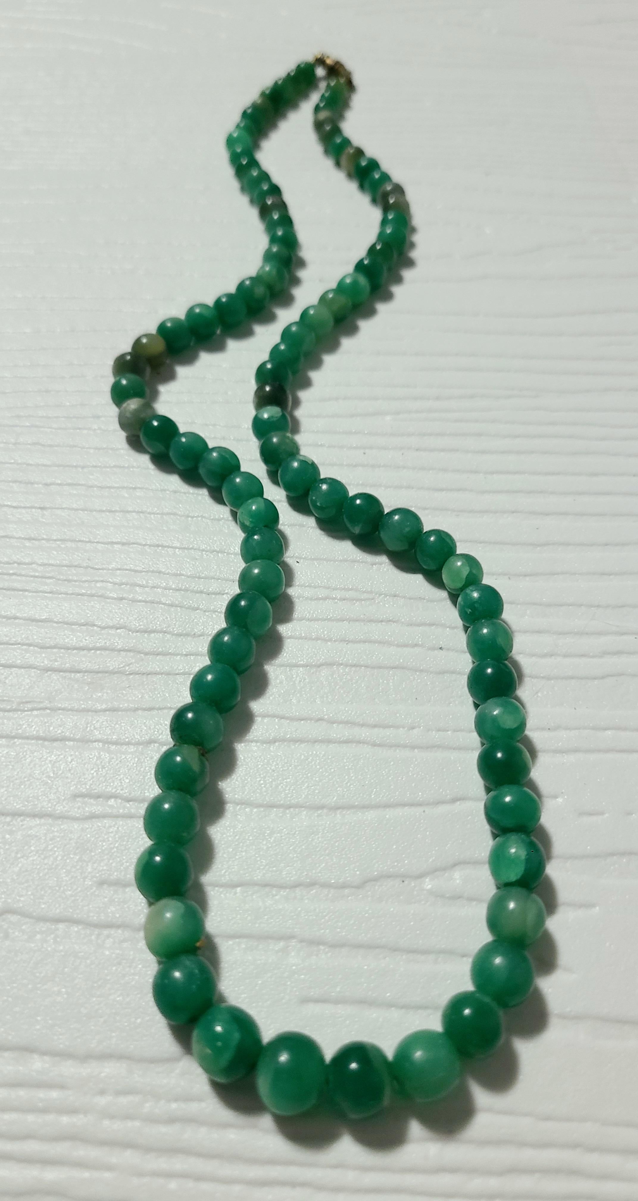 Abgestufte Jade trifft sich an beiden Enden eines Fassverschlusses, um die kaiserliche Perlenkette zu kreieren. 

Jade galt als 