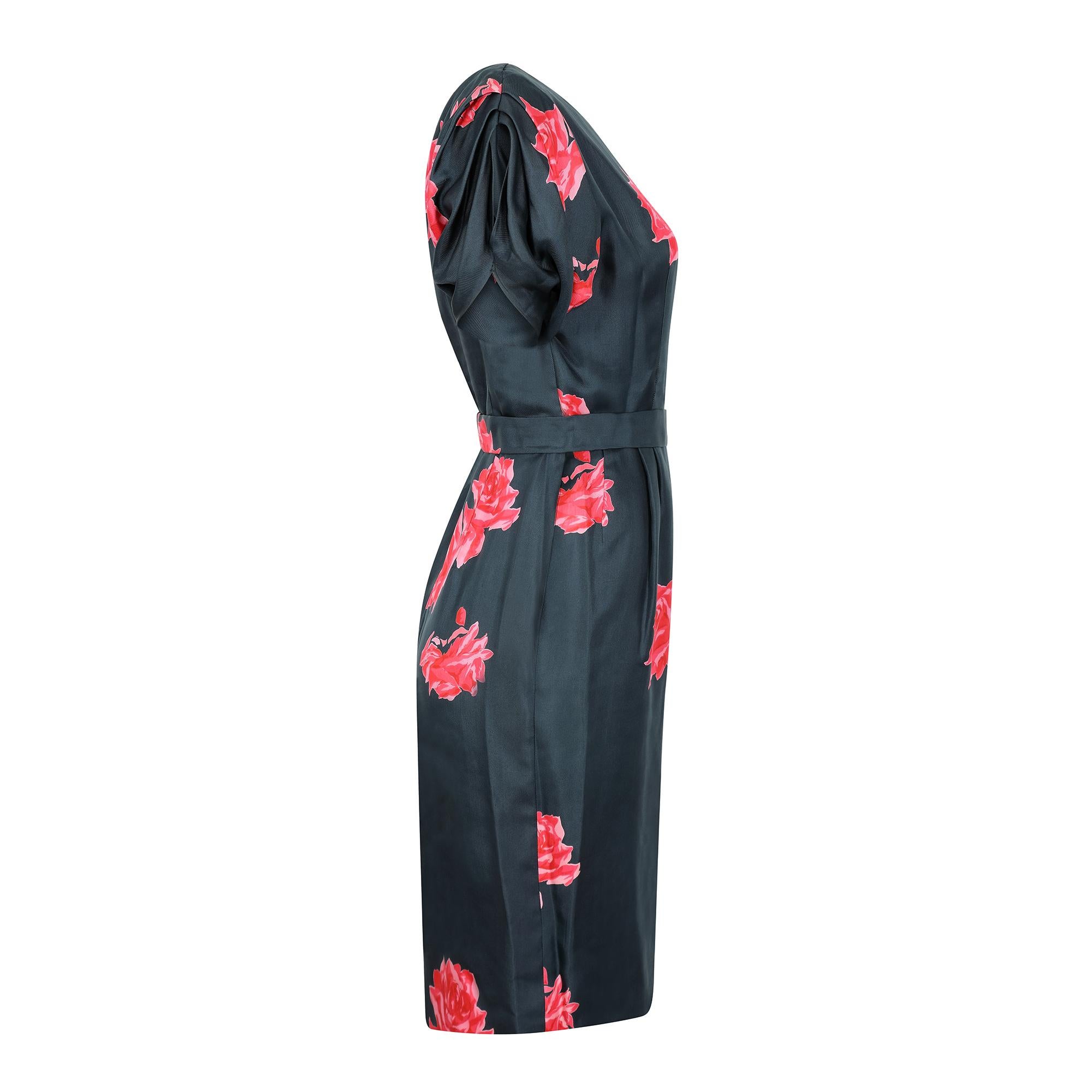 This is a really beautiful example of a late 50s or early 60s design in silk. The large rose print is a blend of pinks and reds which gives the print a painterly quality against the plain nazy background. The dress boasts the most beautiful