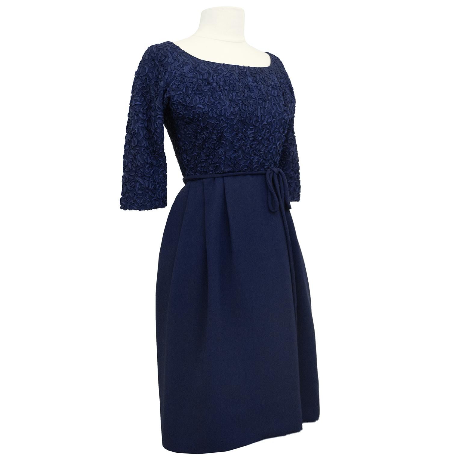 Gorgeous 1950s navy blue cocktail dress. Boat neckline, bracelet length sleeves, fitted bodice and a-line skirt. Bodice is entirely embroidered with monochromatic navy blue ribbon. Thin and delicate waist belt that can be tied in your liking. Tulle