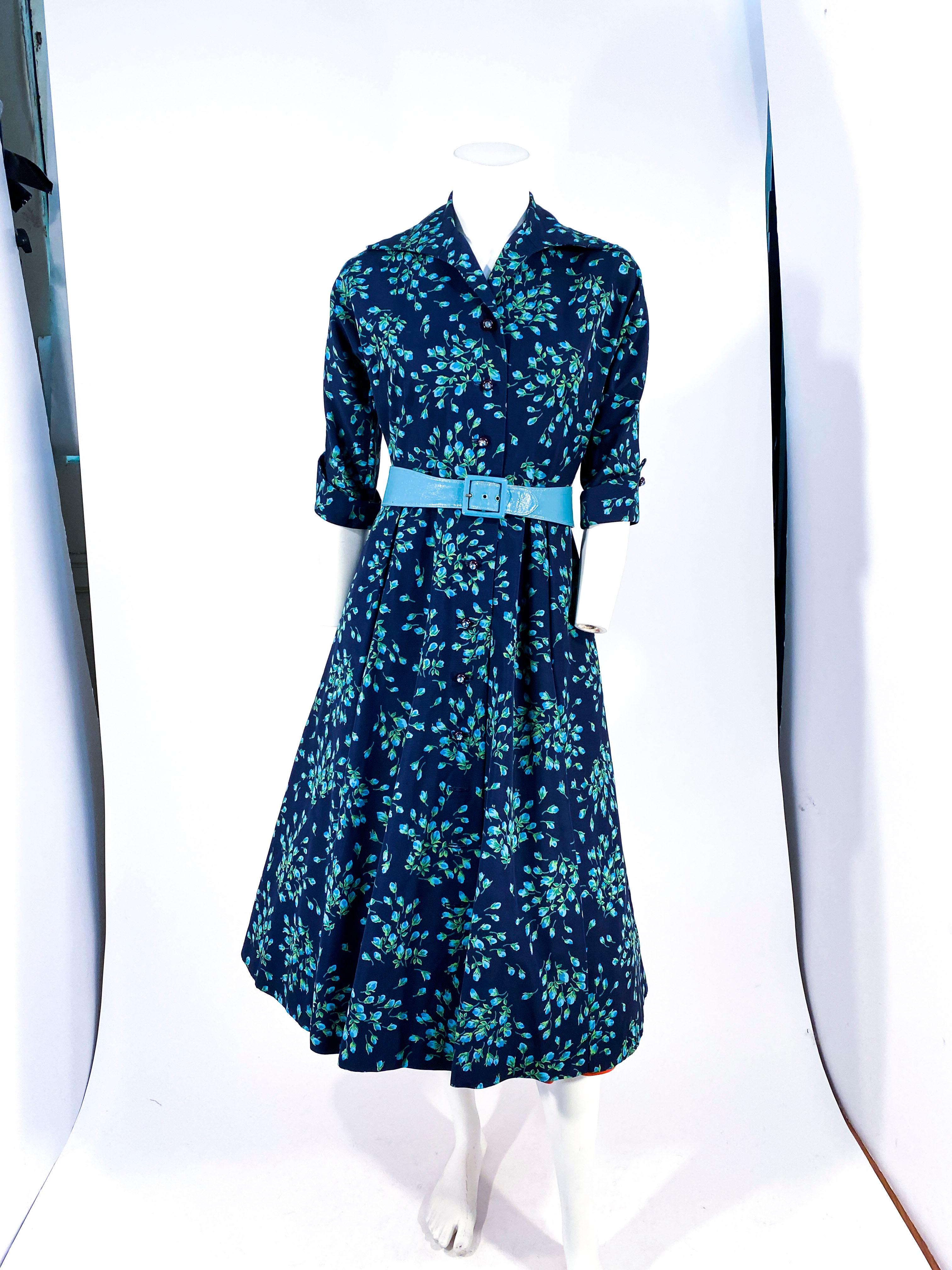 1950er Marineblaues, mit Blumen bedrucktes Kleid aus Rayon Twill mit Taft- und Tüllunterrock aus Inteiro. Das Kleid ist mit großen, strassbesetzten Knöpfen in der Mitte, einem vergrößerten, spitzen Kragen und ellbogenlangen Ärmeln mit Manschetten