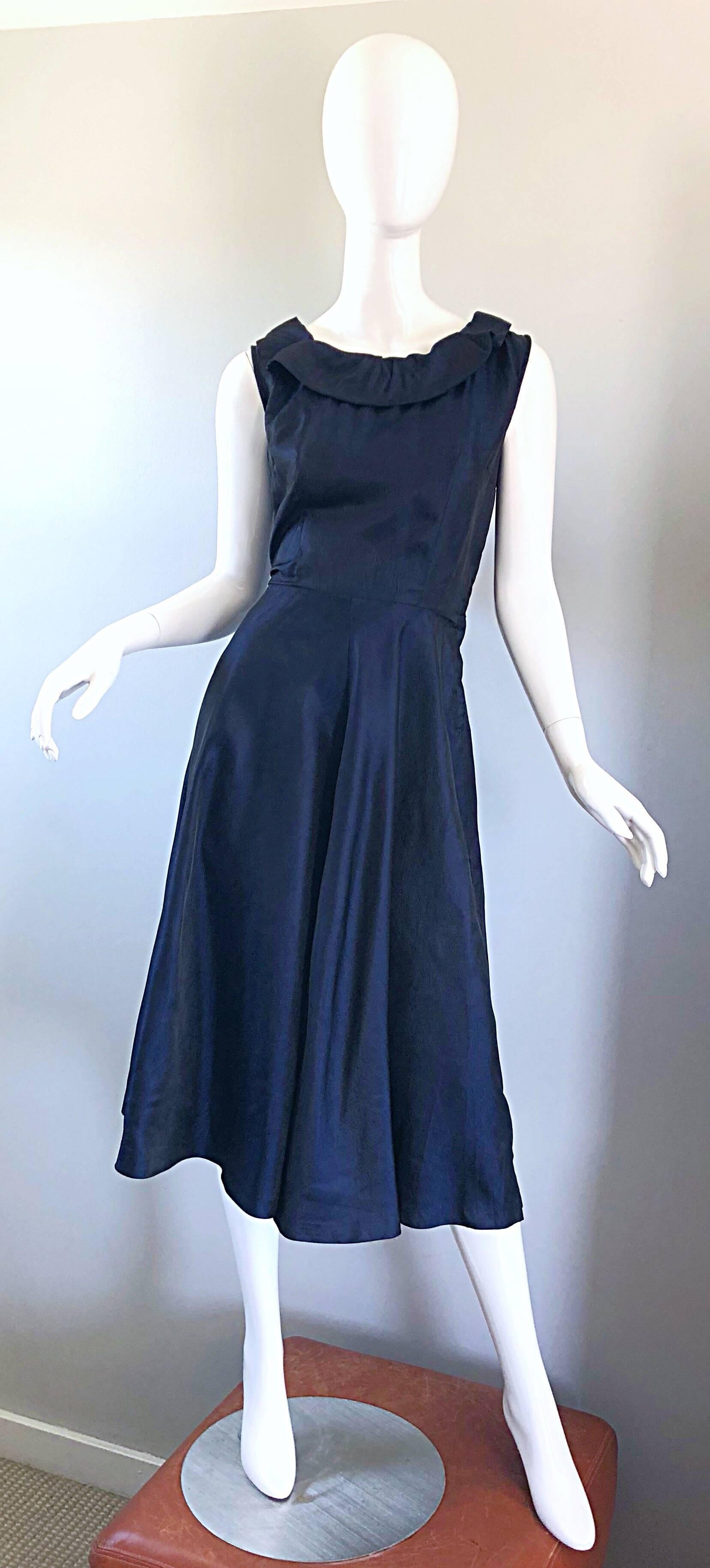 Beautiful 1950s navy blue silk dress! Features a fitted bodice with chic ties at top back neck. Forgiving full skirt. Full metal zipper at the side bodice. Extremely well constructed with a heavy eye to detail. Great belted or alone for any day or