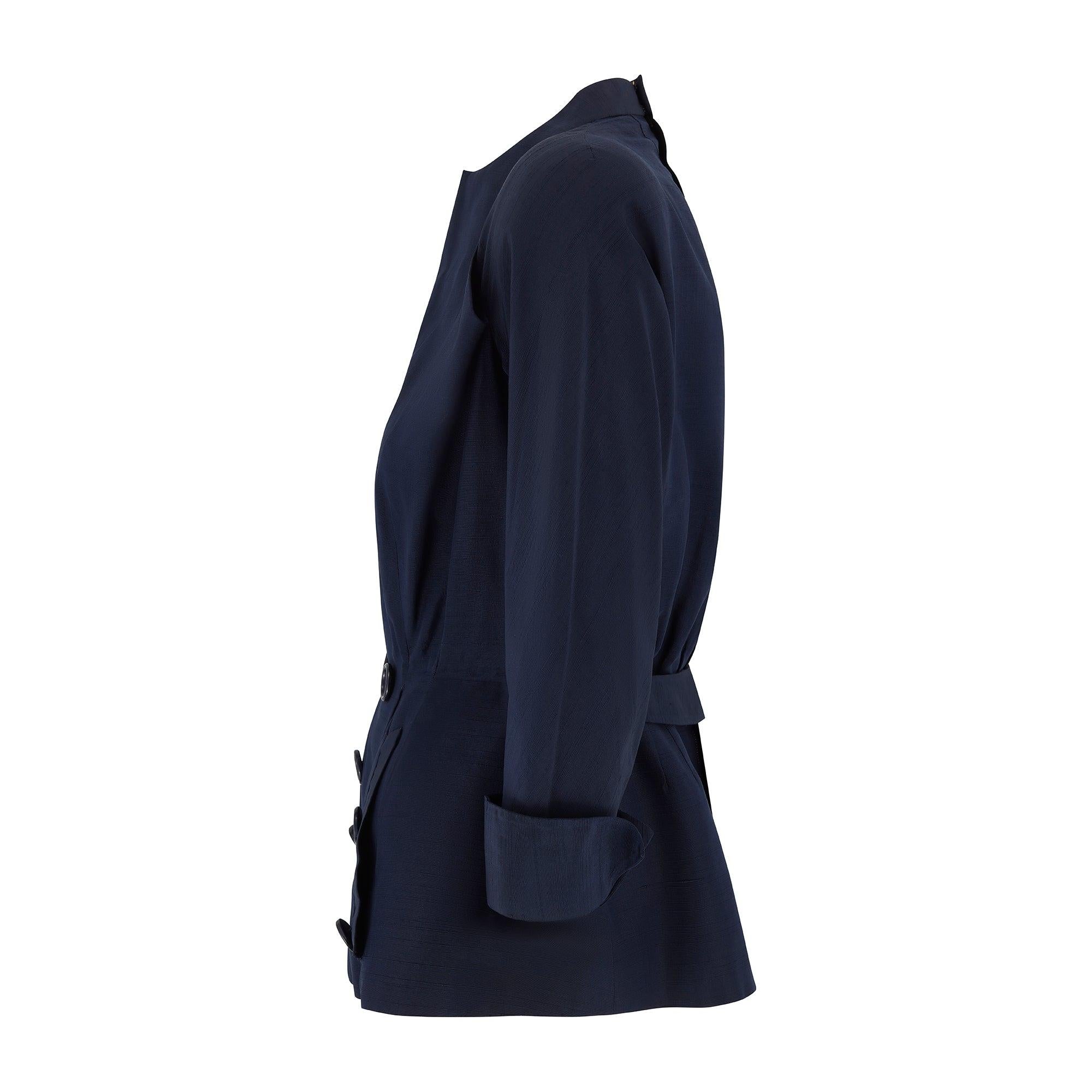 This early 1950s navy shot silk jacket is unlabelled haute couture circa 1950-51. Of complex construction, it is cut in a classic New Look 'bar' style shape, with rounded front hem, slender waist and accentuated slope of the basque bodice. It has