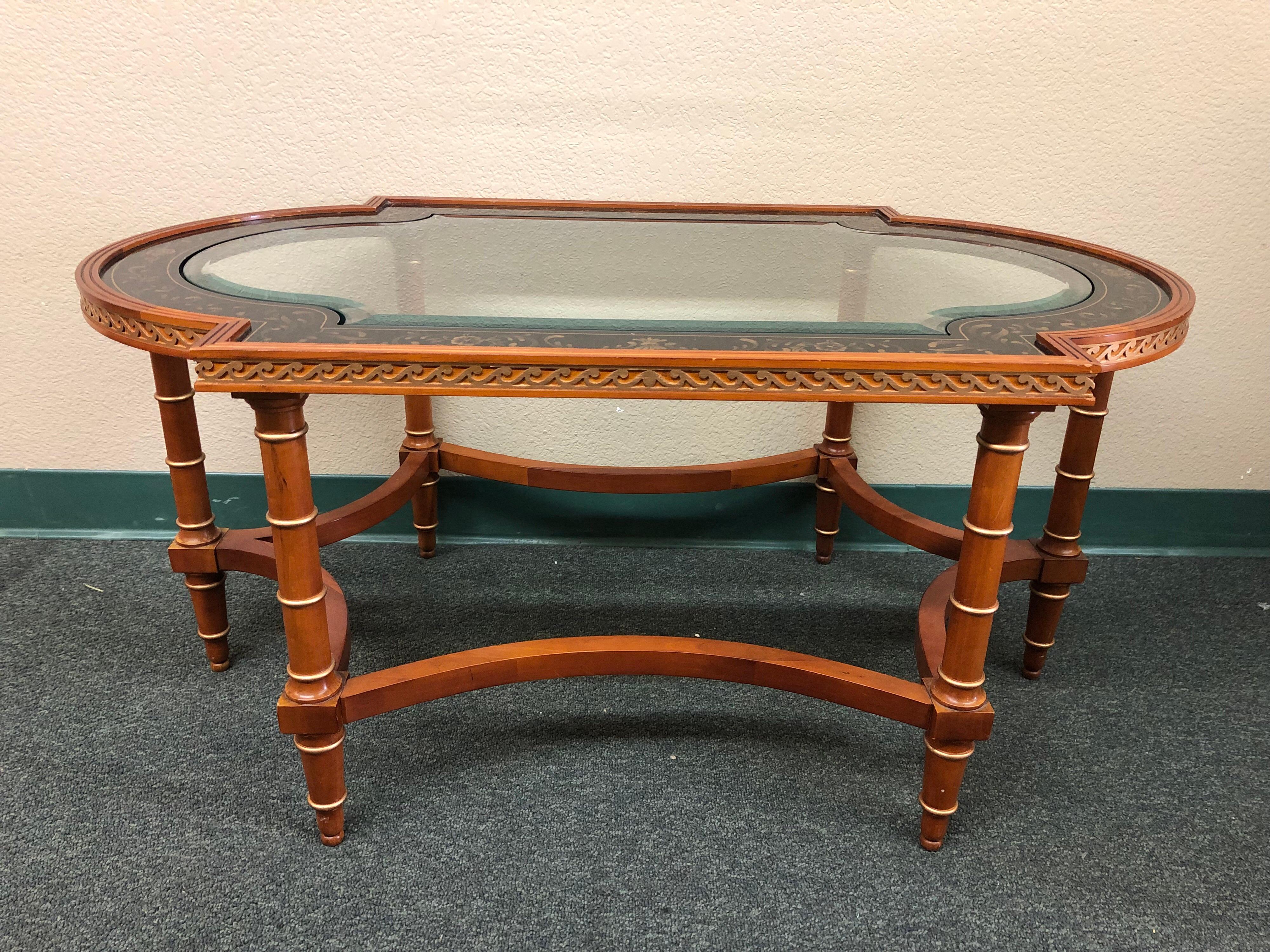 A unique cocktail table by John Widdicomb. Beautifully stylized with hand-painted glass inset on a molded edge, faux bamboo frame and demilune ends, it is a statement unto itself.
 