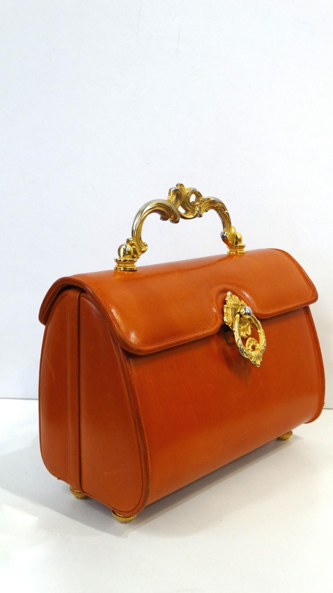 The Most Adorable Bag Is Here And It Screams Vintage! Circa 1950s, this Netti Rosenstein leather barrel bag is a beautiful burnt orange color and features Victorian/Baroque style gold plated hardware. Includes engraved feet on the bottom and a