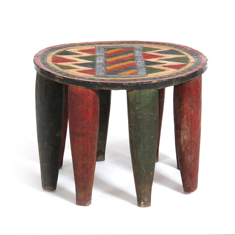 An eight-leg “Nupe” stool hand carved from a single piece of wood painted in an abstract pattern.