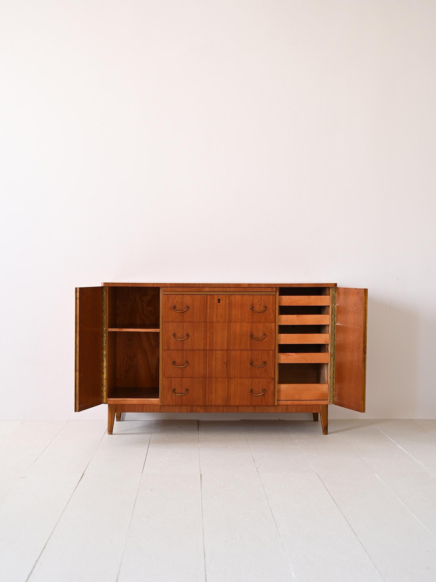 Scandinavian sideboard with central drawers.

This piece of furniture with a vintage flavor is characterized by the presence of the golden handles on the drawers and the division of space into three compartments. On the two sides there is