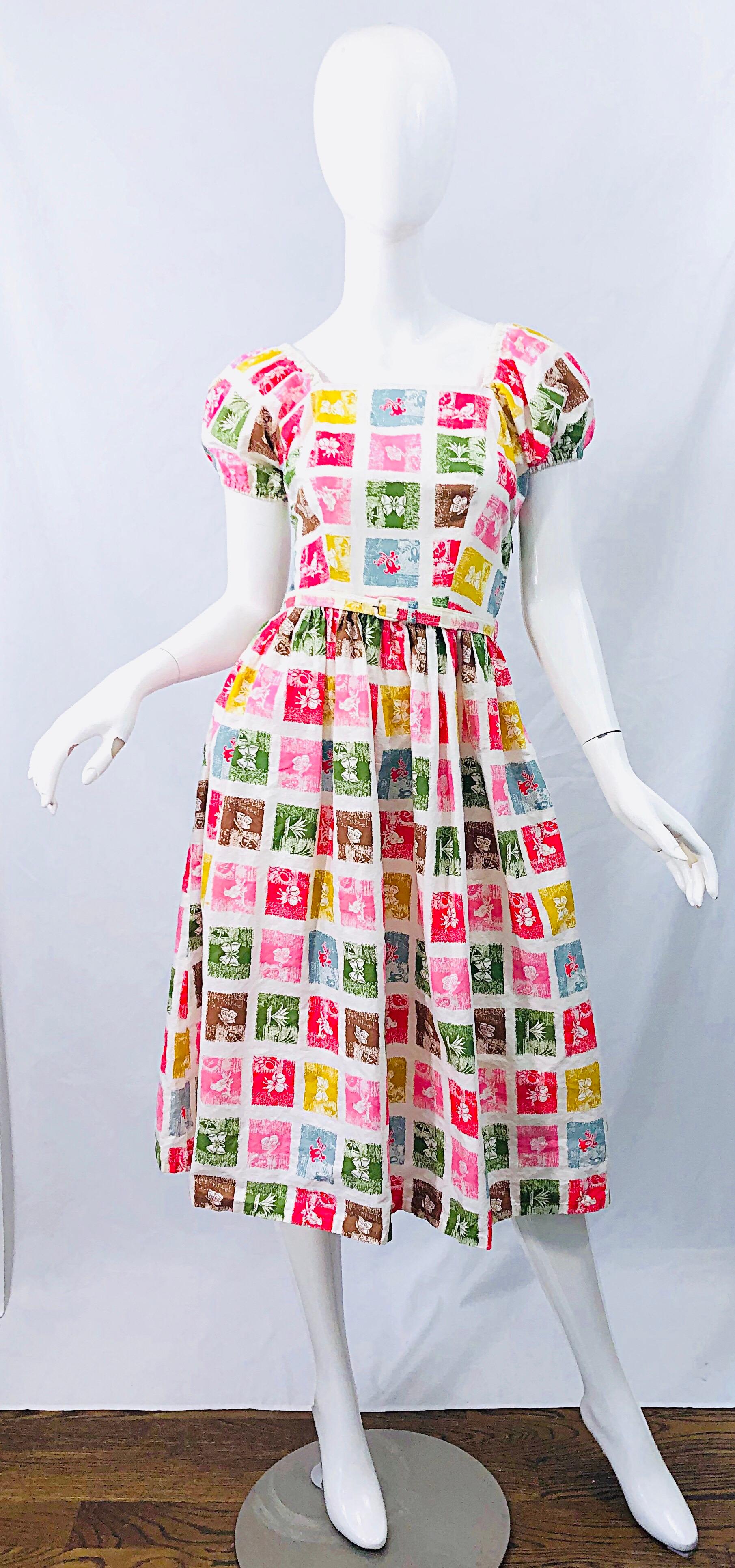 Super chic 1950s novelty print colorful fit n' flare belted cotton dress ! Features a white background with vibrant pops of pink, chartreuse green, yellow, brown and red throughout. Prints of birds, flowers and butterflies throughout. Stylish puff