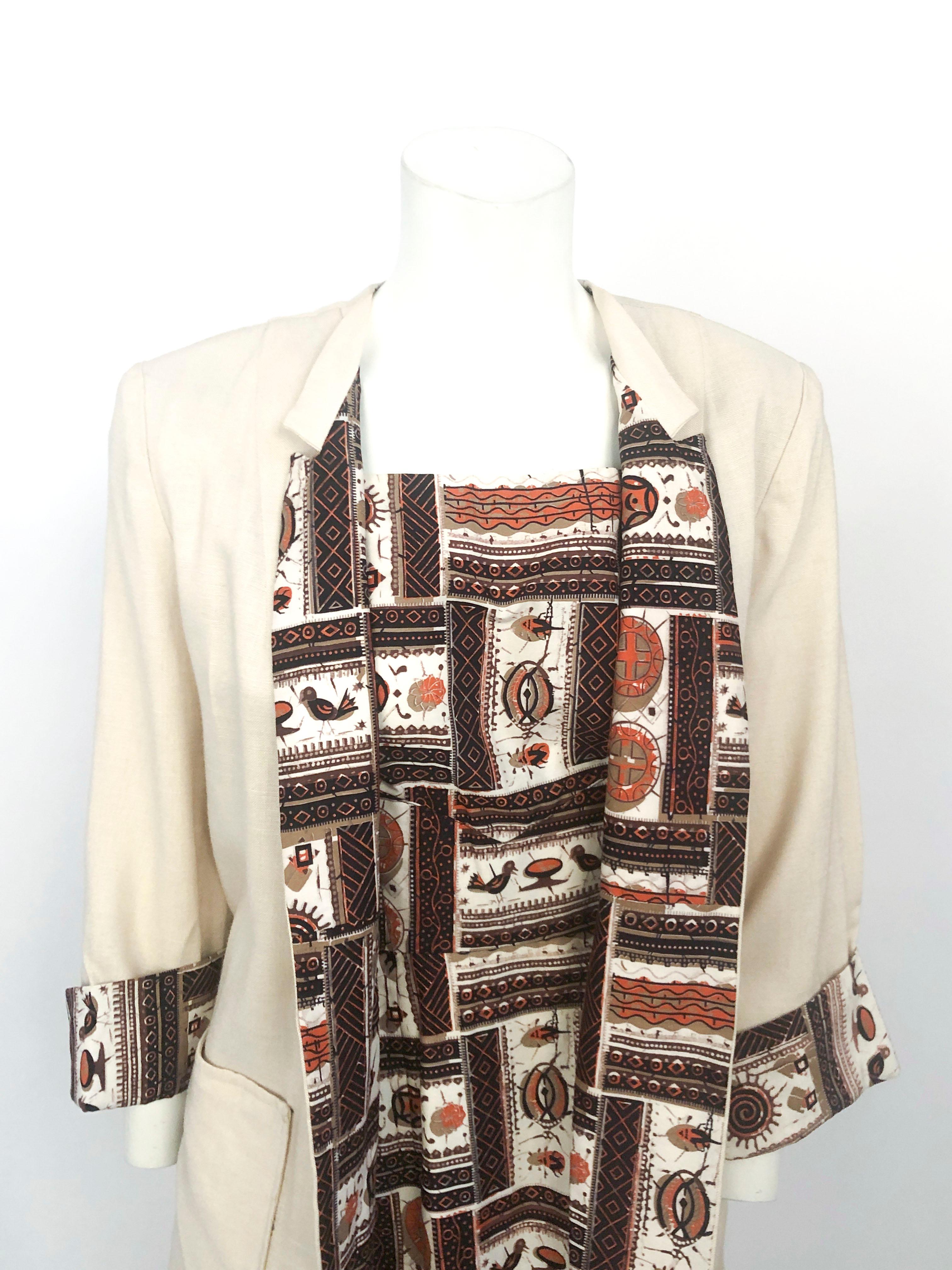 1950s cotton day dress featuring novelty tribal print that has birds, insects, and sun motif in tones of brown beige and orange. The dress has a square neckline and pleated bodice to complement the straight skirt. The coat is made of linen with thin