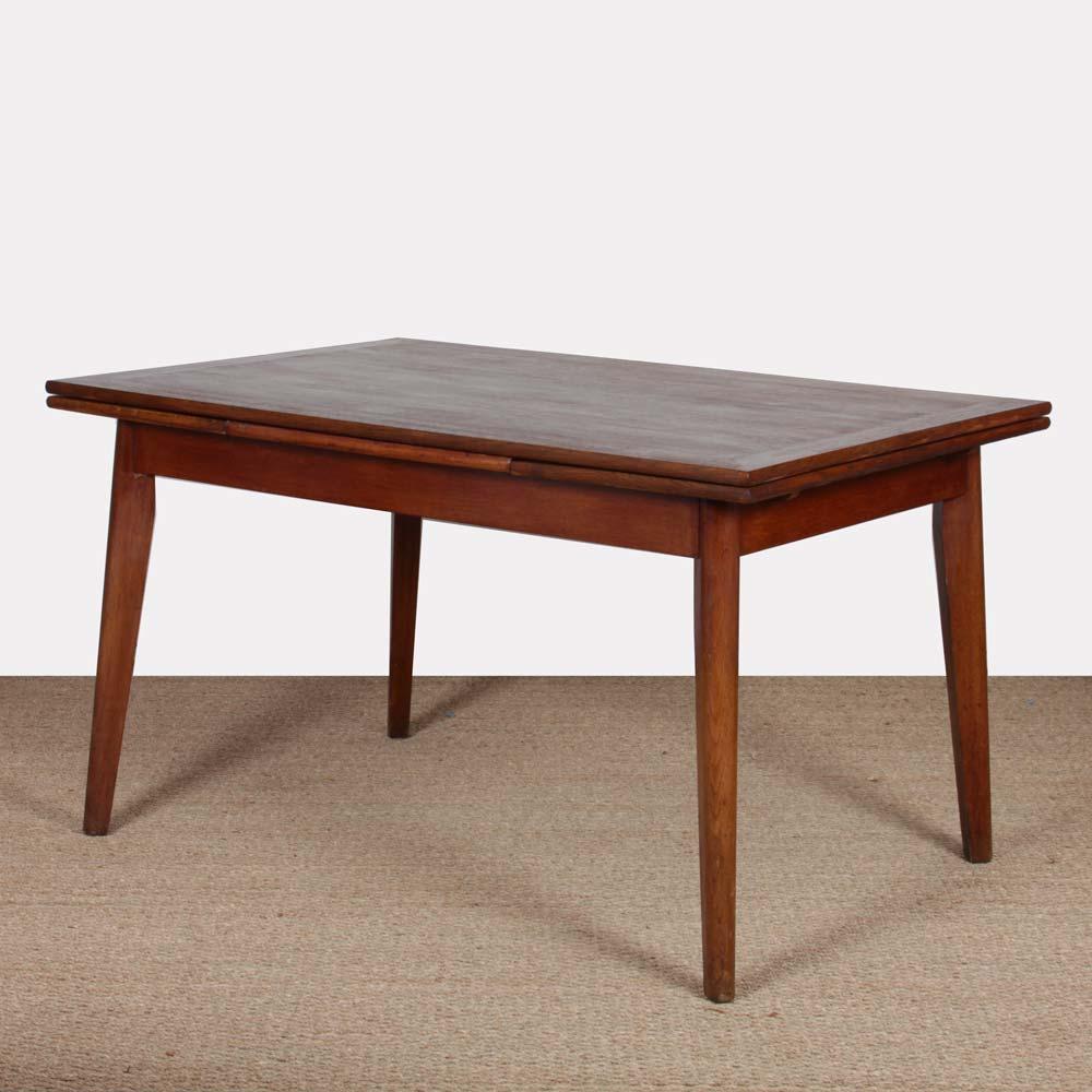 This oak dining table dates from the 1950s. It was made in France during the Reconstruction period. It includes two integrated 40 cm extensions. This piece is in good original condition. The top has been restored. 