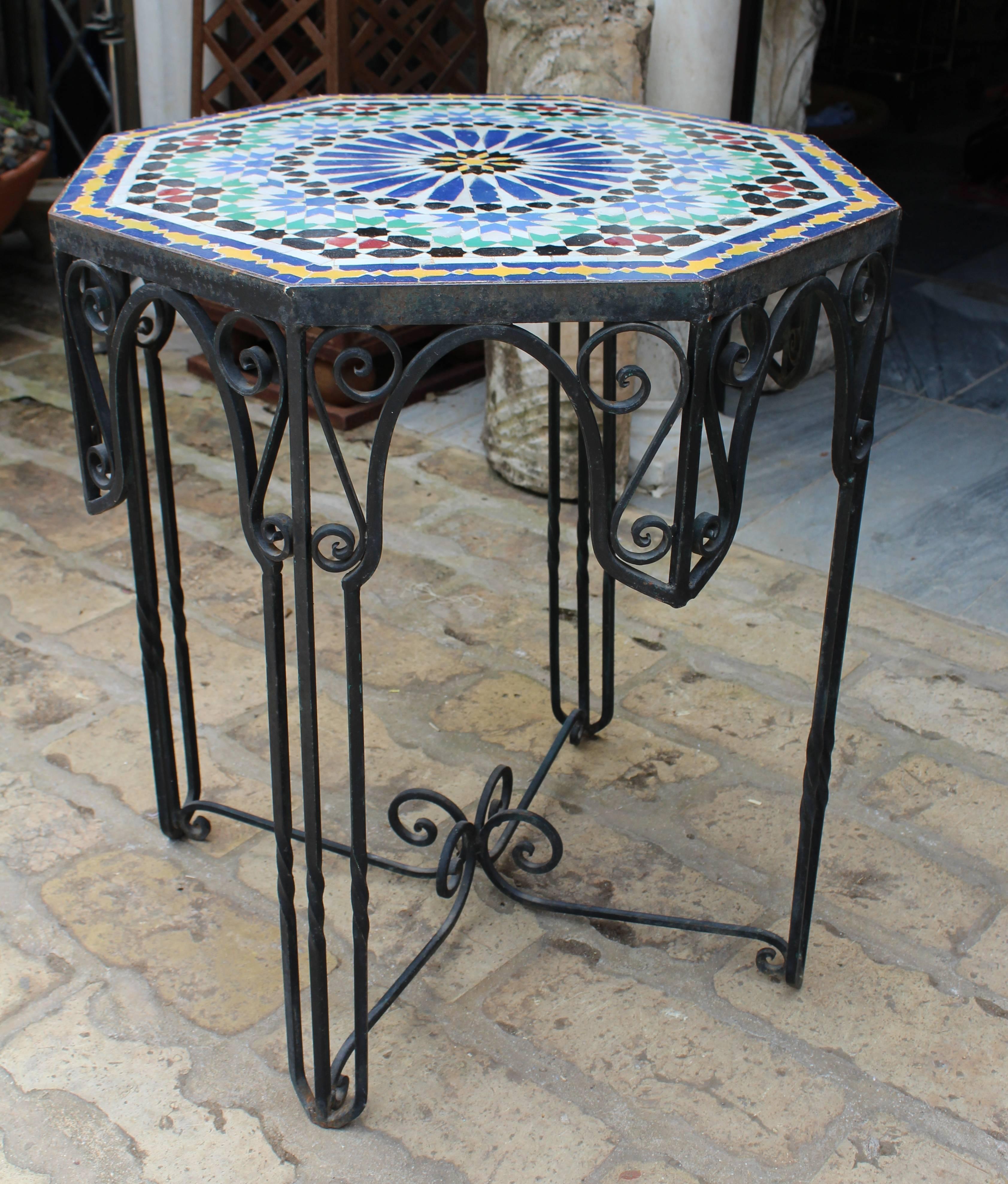1950s octagonal grazed ceramic Andalusian geometric mosaic table on a wrought iron base decorated with scrolls.