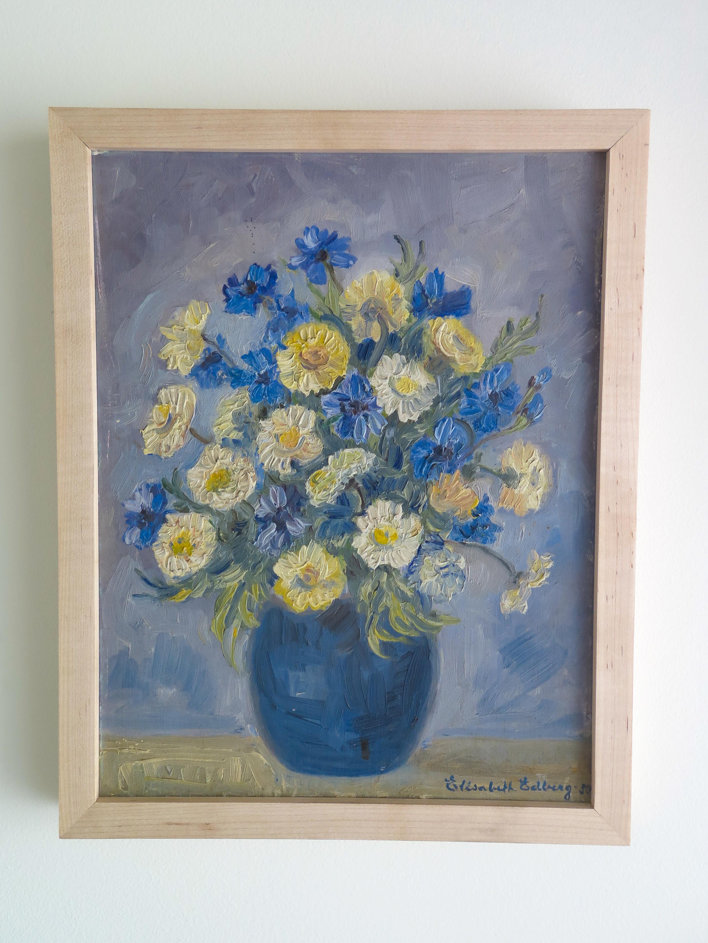 Beautiful oil painting on canvas of yellow and blue flowers in a vase. Great colors and texture. Signed by artist Elizabeth Goldberg in lower right hand corner. Newly framed in a light maple wood frame.