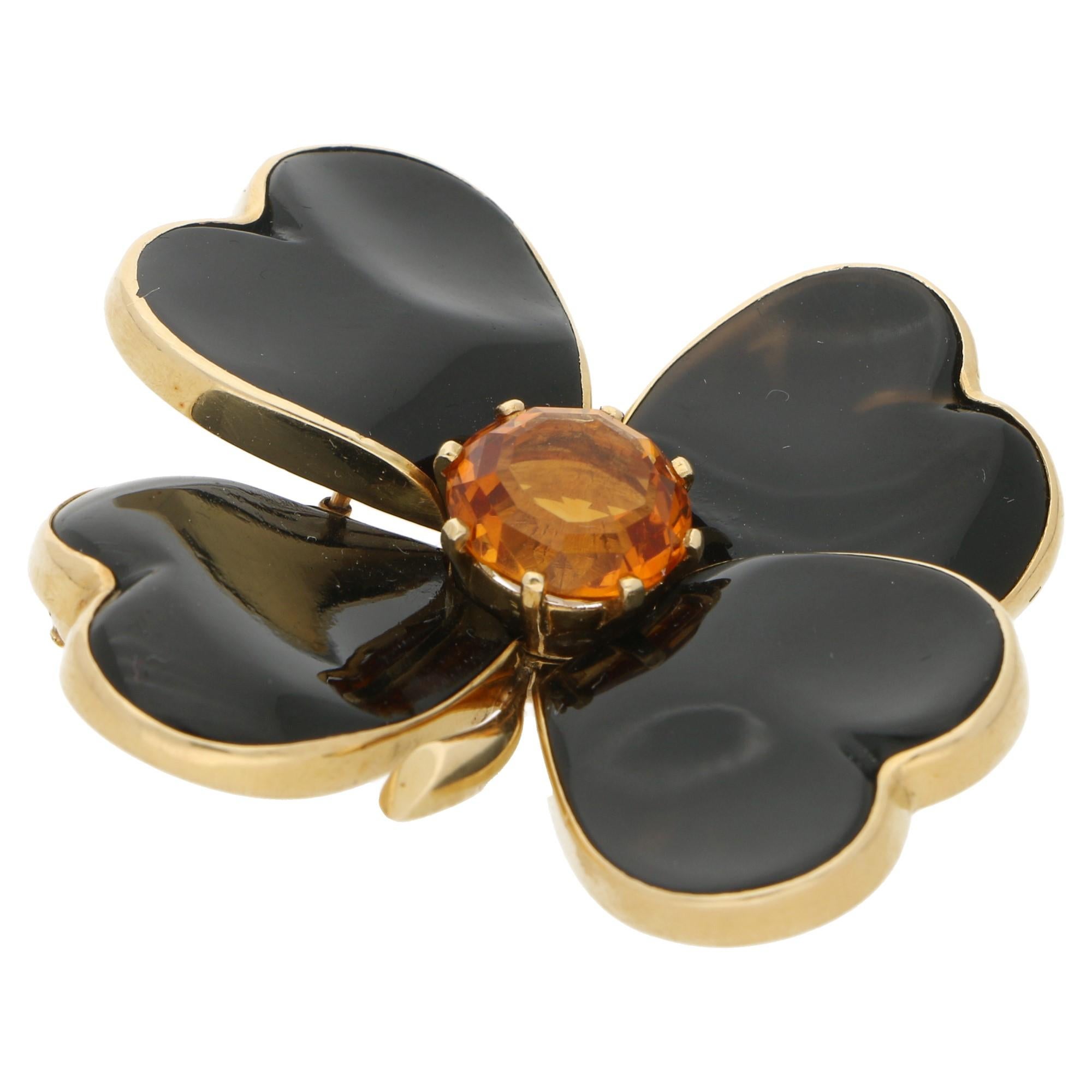 A striking onyx and citrine floral brooch. 
The brooch is formed of heart shaped petal motifs set with black onyx which in 18ct yellow gold. 
The brooch is further embellished with an eight claw-set round cut citrine at the centre and secured to the
