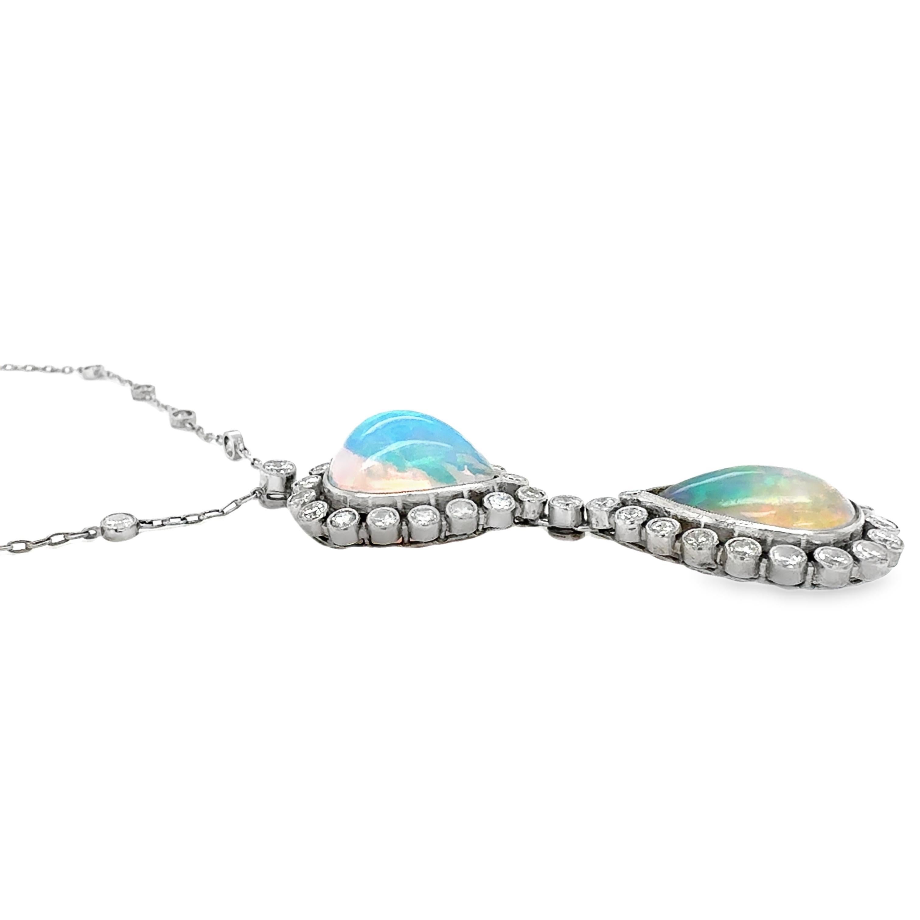 This enchanting mid-century pendant necklace features two luminous pear-shaped cabochon white opals, totaling approximately 8.50 carats. Each opal shimmers with a mesmerizing play-of-color and is framed by a halo of round brilliant cut diamonds—35