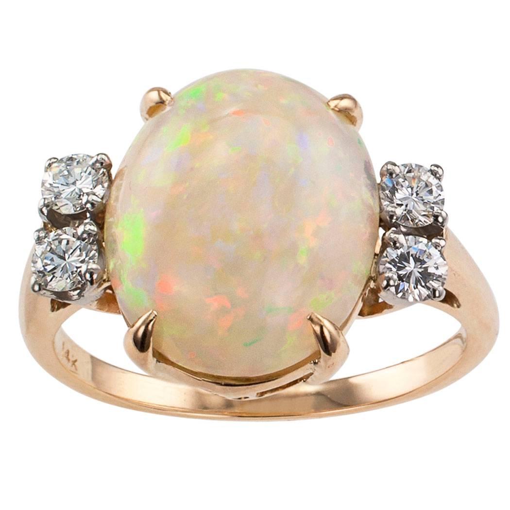 Midcentury opal and diamond ring circa 1950.  Centering upon a bright and colorful oval opal weighing approximately 4.50 carats.   It is a stone of moderate size, however, it is literally bursting with colors that jump out at the light.  It is the