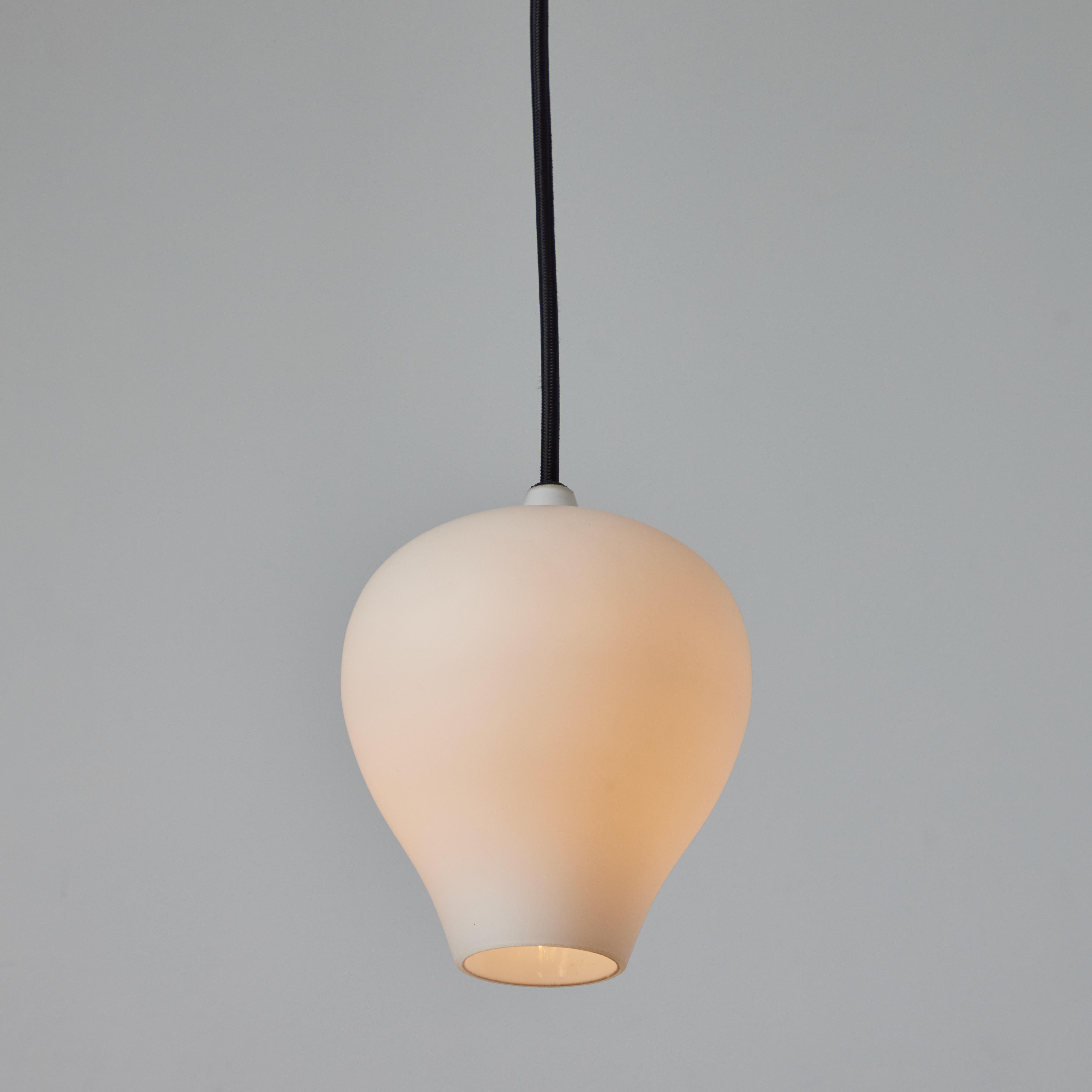 Ciondoli in vetro opalino degli anni '50 di Alf Svensson per Bergboms Belysning. Realizzato in vetro opalino, con cavo in tessuto nero e baldacchino in ottone lucido. Un design moderno scandinavo lirico ed elegante, con una forma scultorea tipica